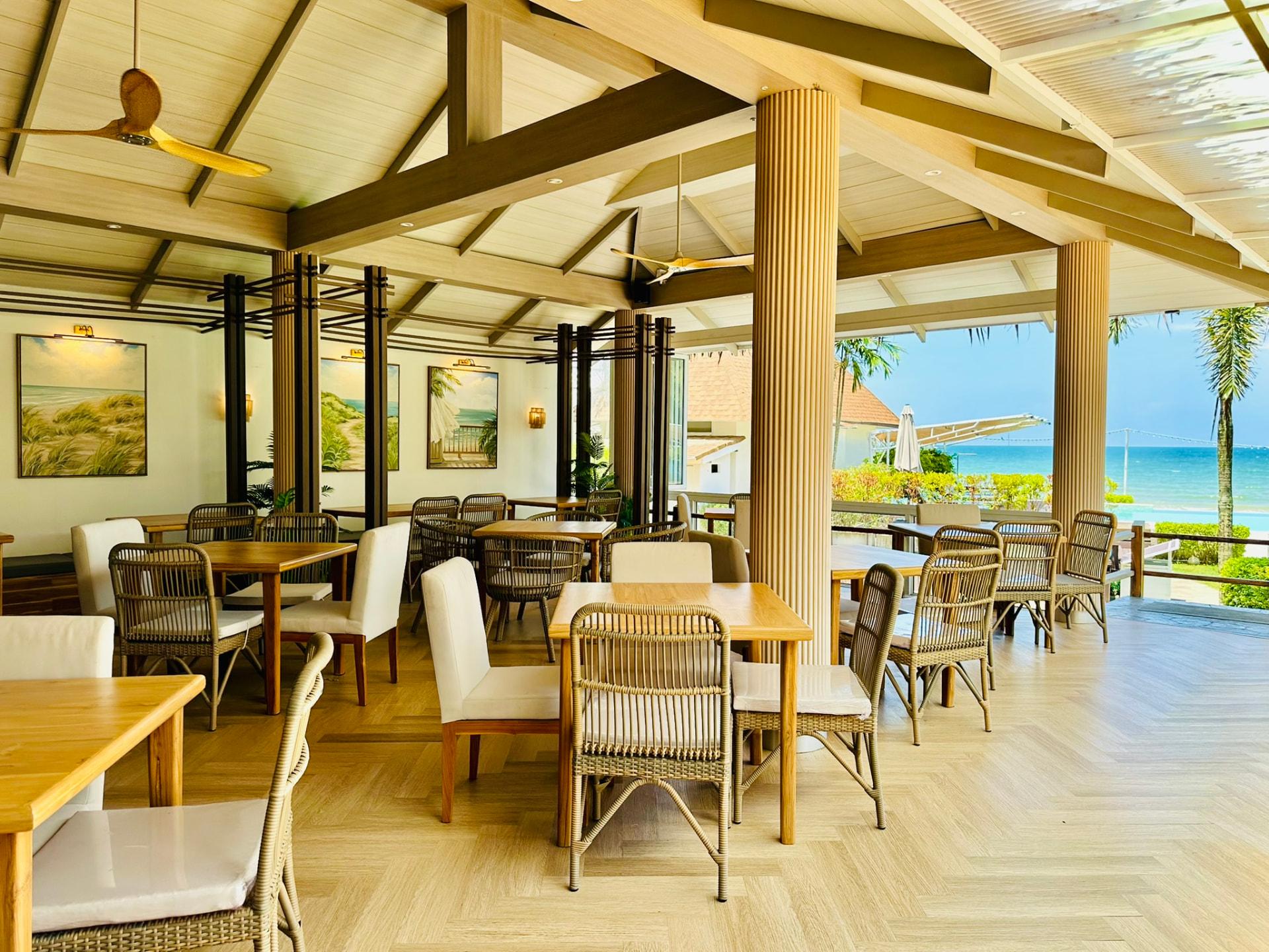 Tables at Breezy Bites opening onto the pool, palms and turquoise sea