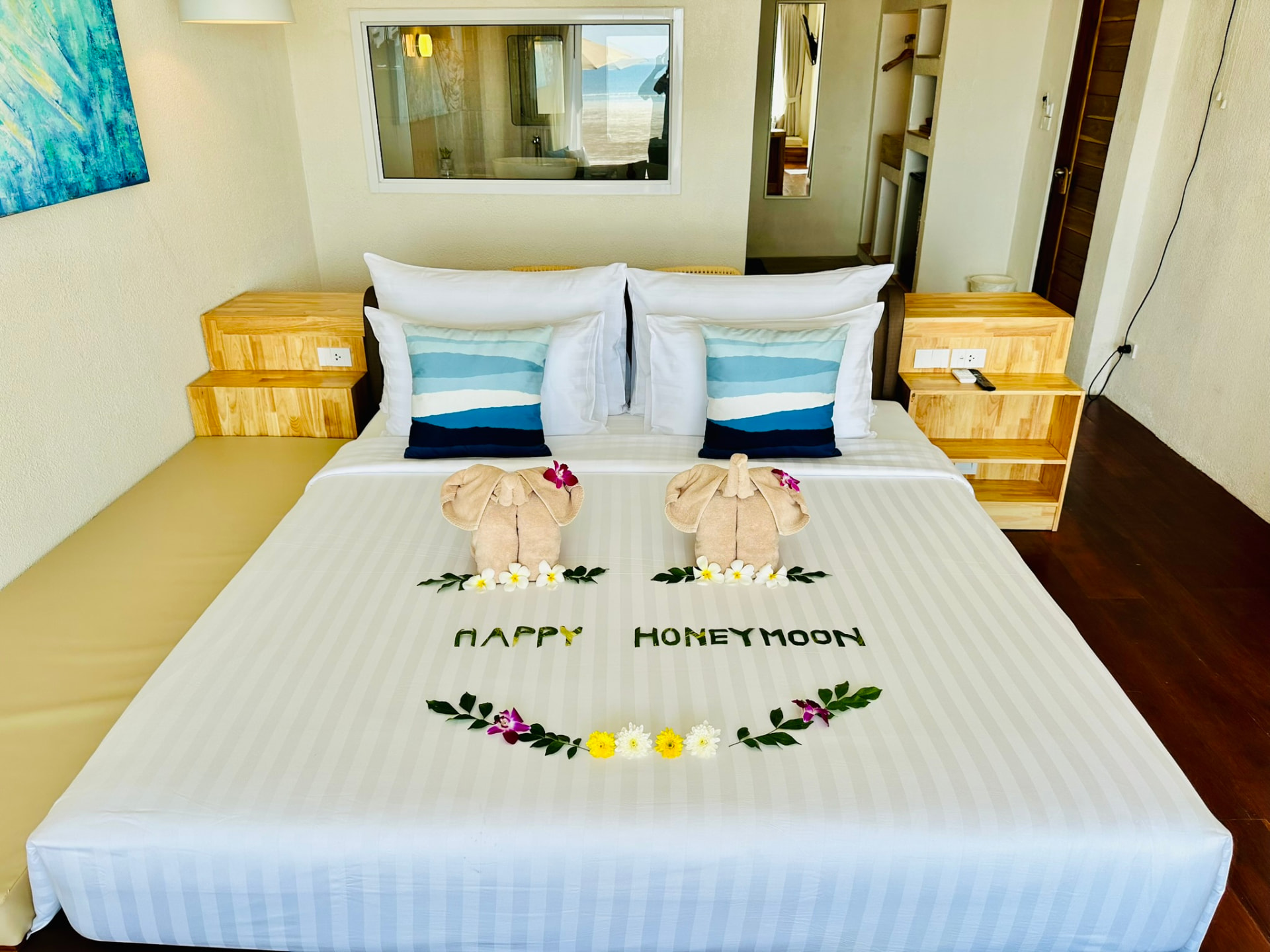 King bed dressed with striped linen, blue cushions and towel elephants