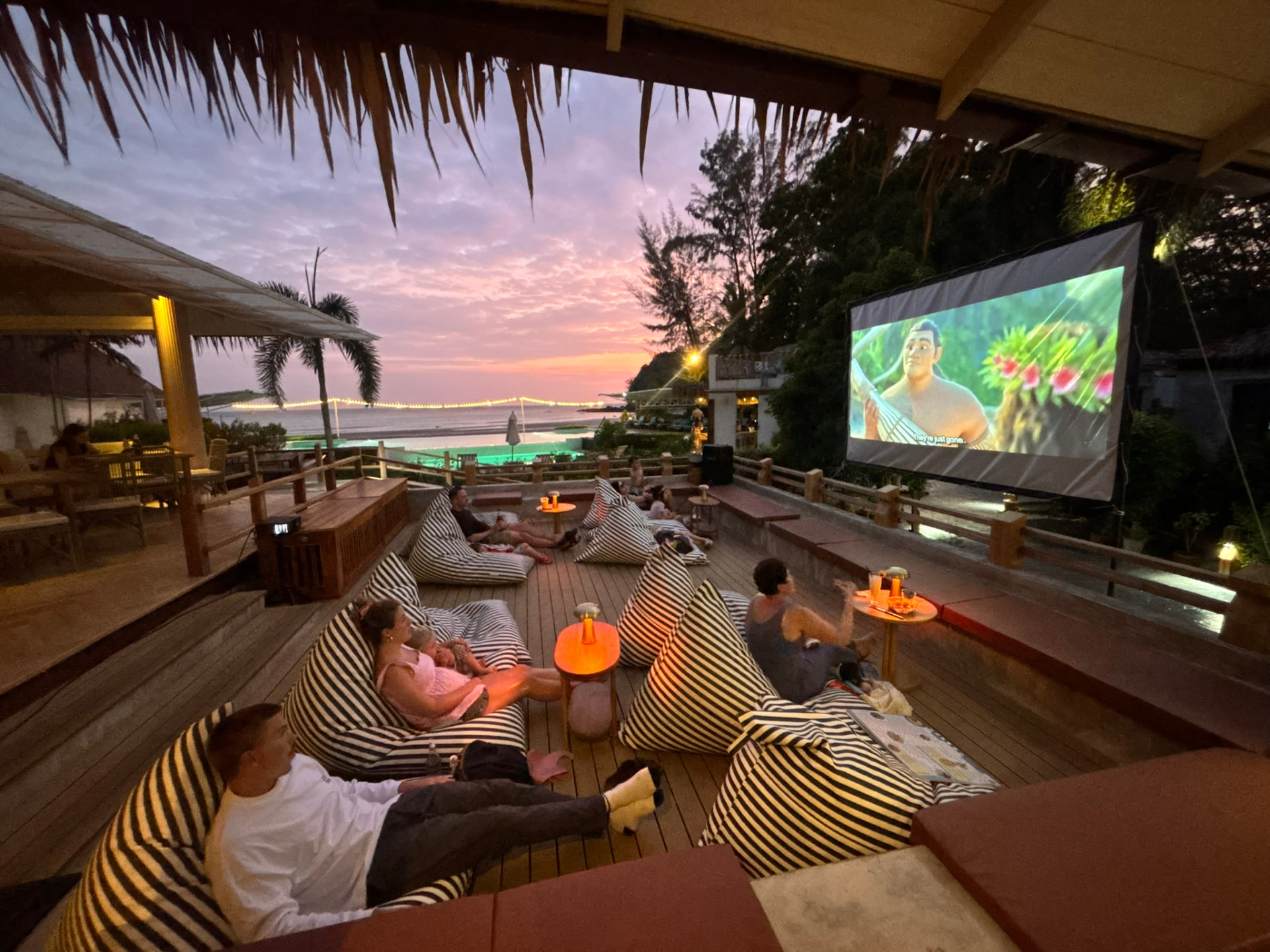 Pink sunset over the sea while guests watch the film from bean bags