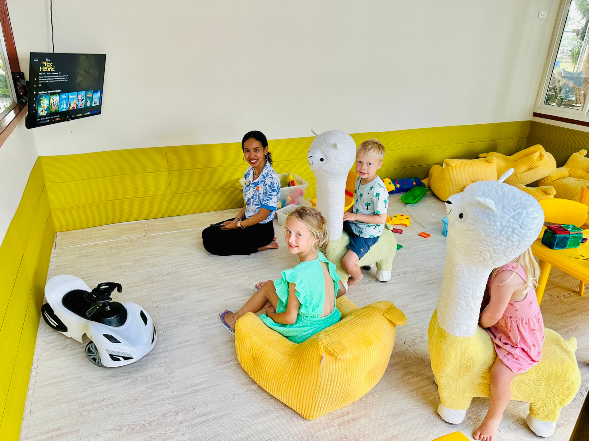 A TwinBay team member sitting with children playing in the Kids Room