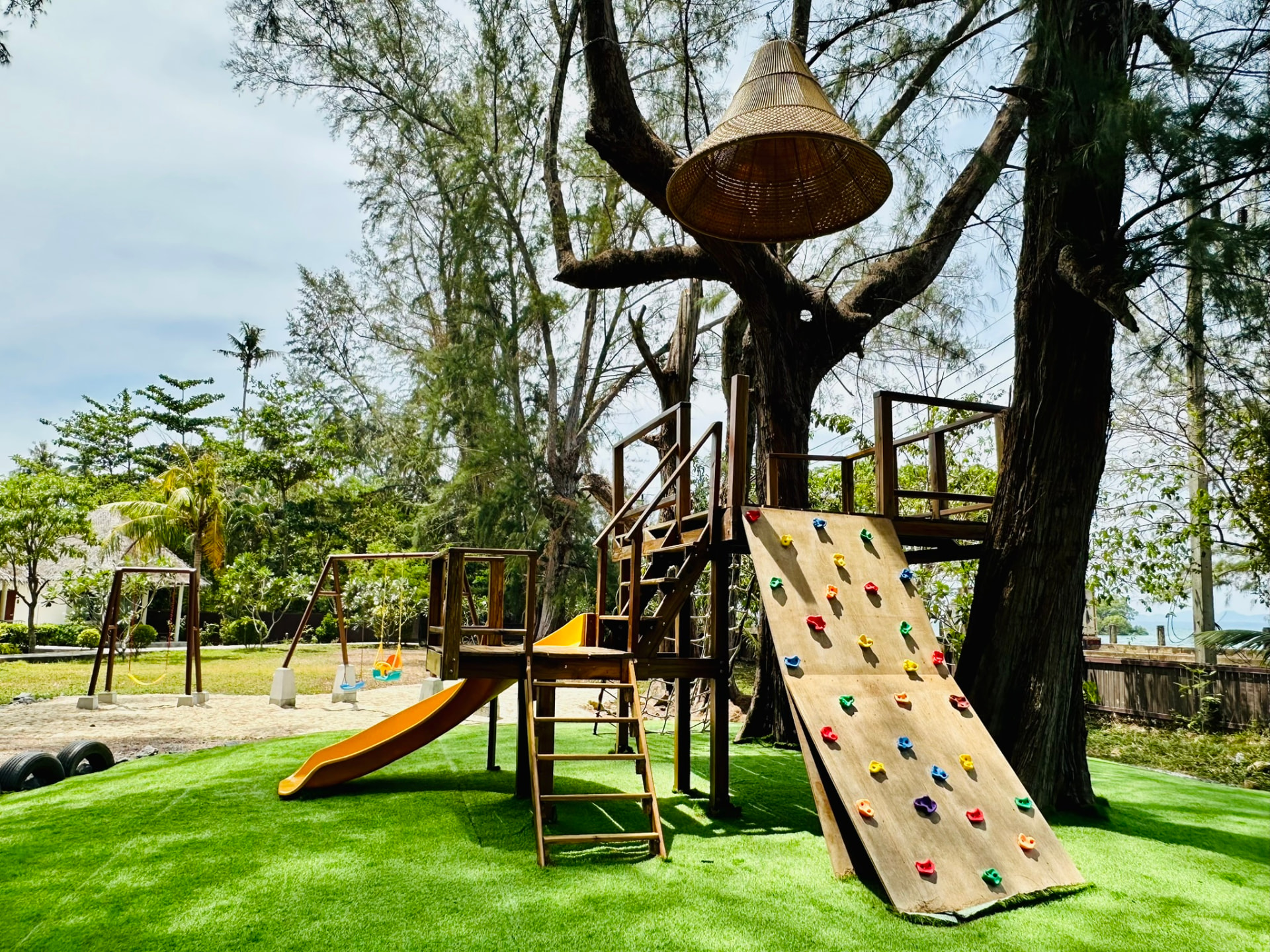 Climbing wall and wooden play frame on the green lawn with the sea behind