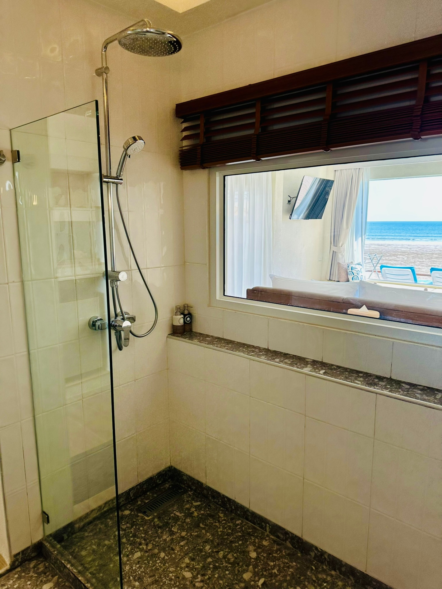 Glass walk-in rain shower with an interior window looking through to the sea