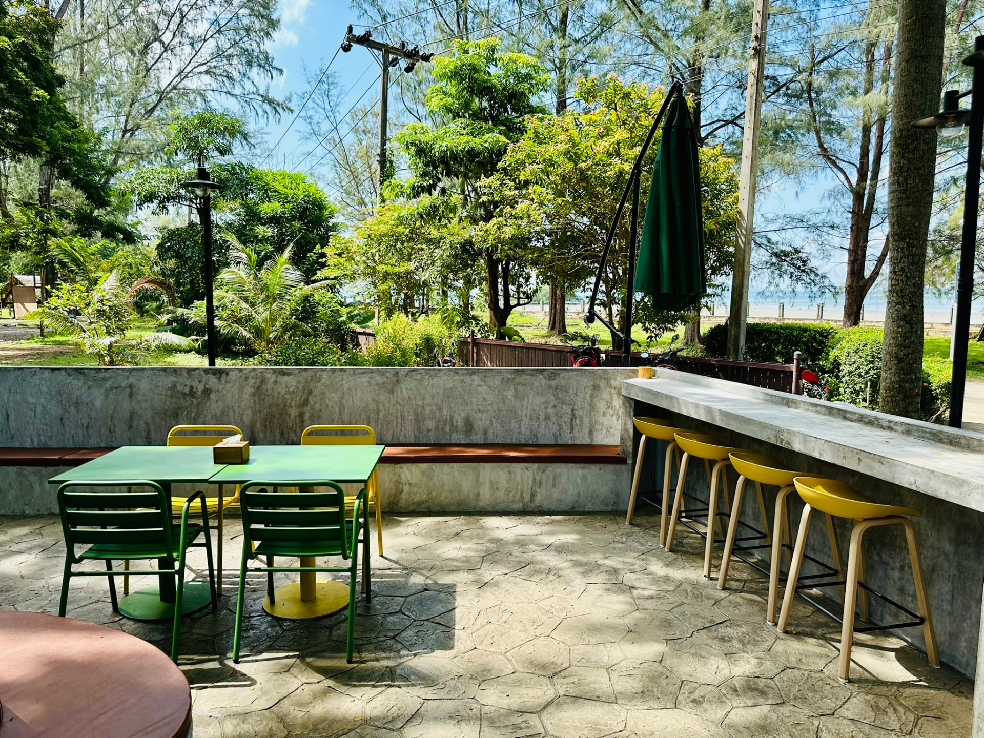 The long concrete bar counter and yellow stools at PineNapple Cafe facing the beach
