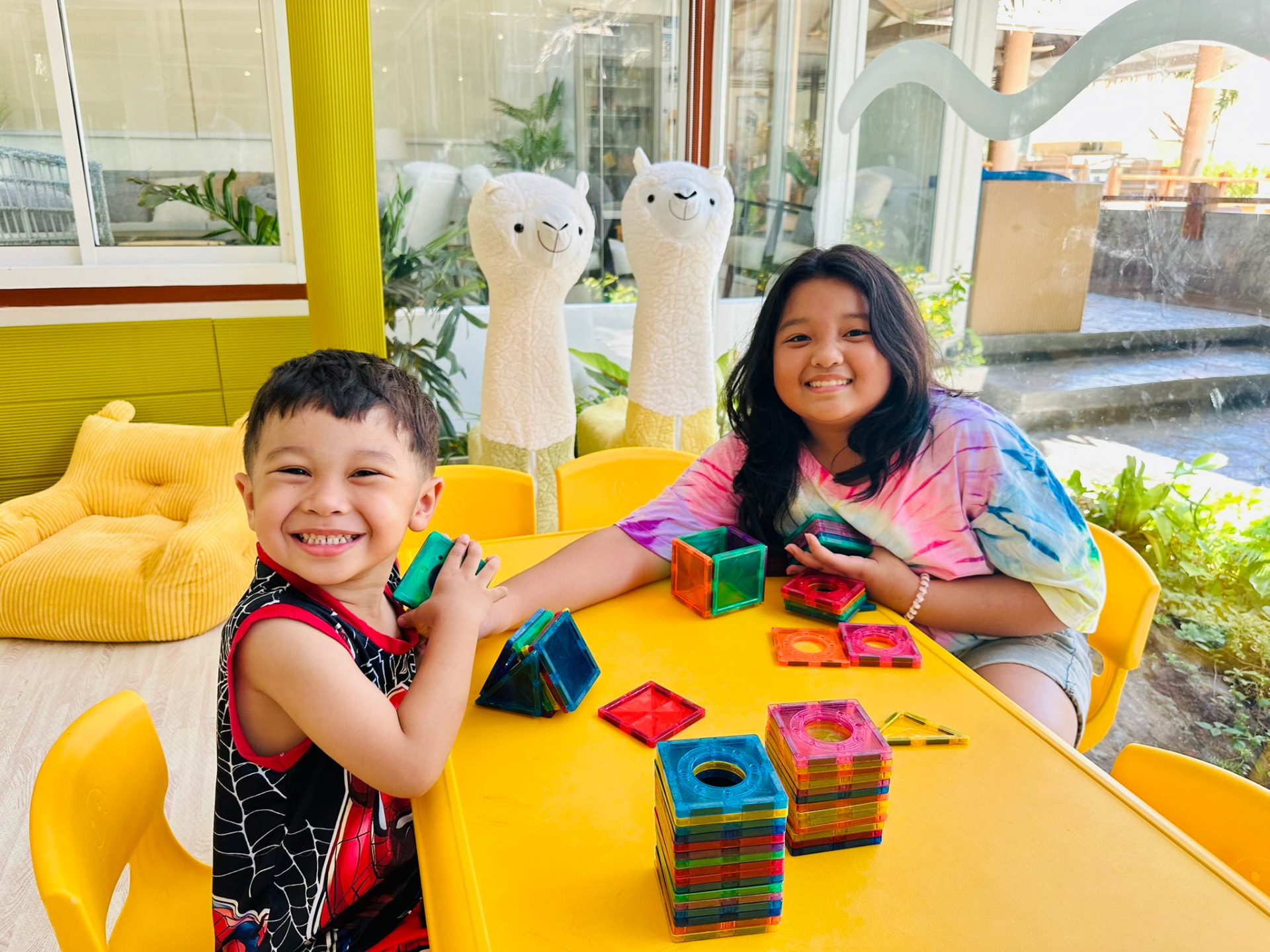 A boy and a girl smiling over their magnetic tile towers in the Kids Room