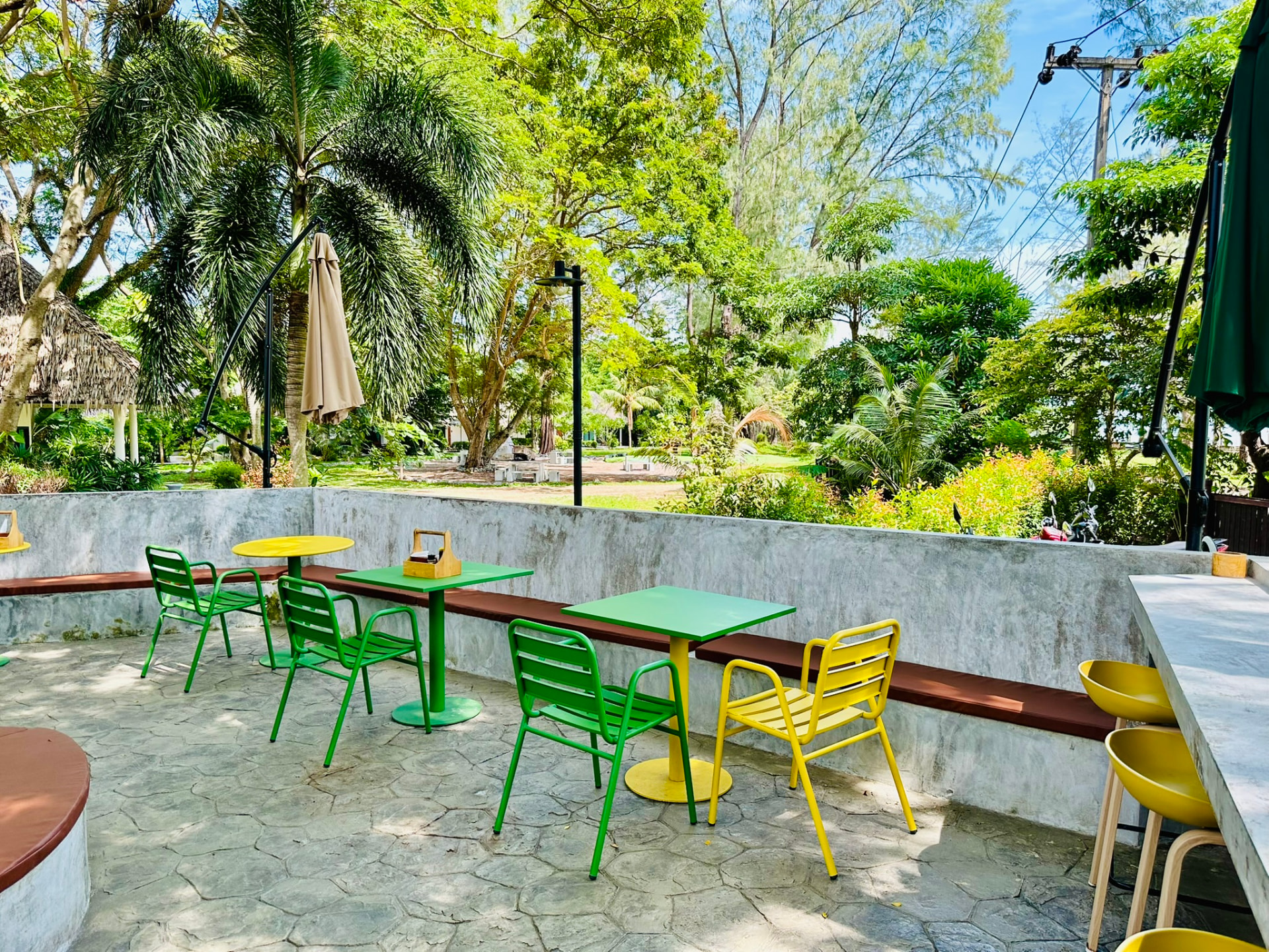 Green tables and chairs at PineNapple Cafe looking out over the resort gardens