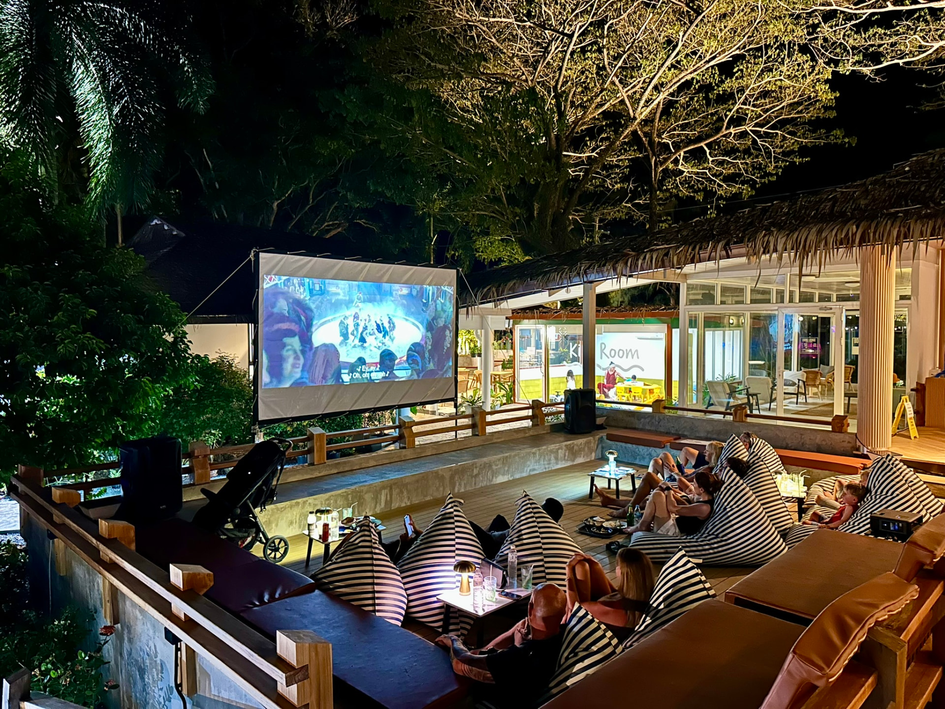 The screen glowing after dark with guests relaxed on bean bags at Breezy Bites