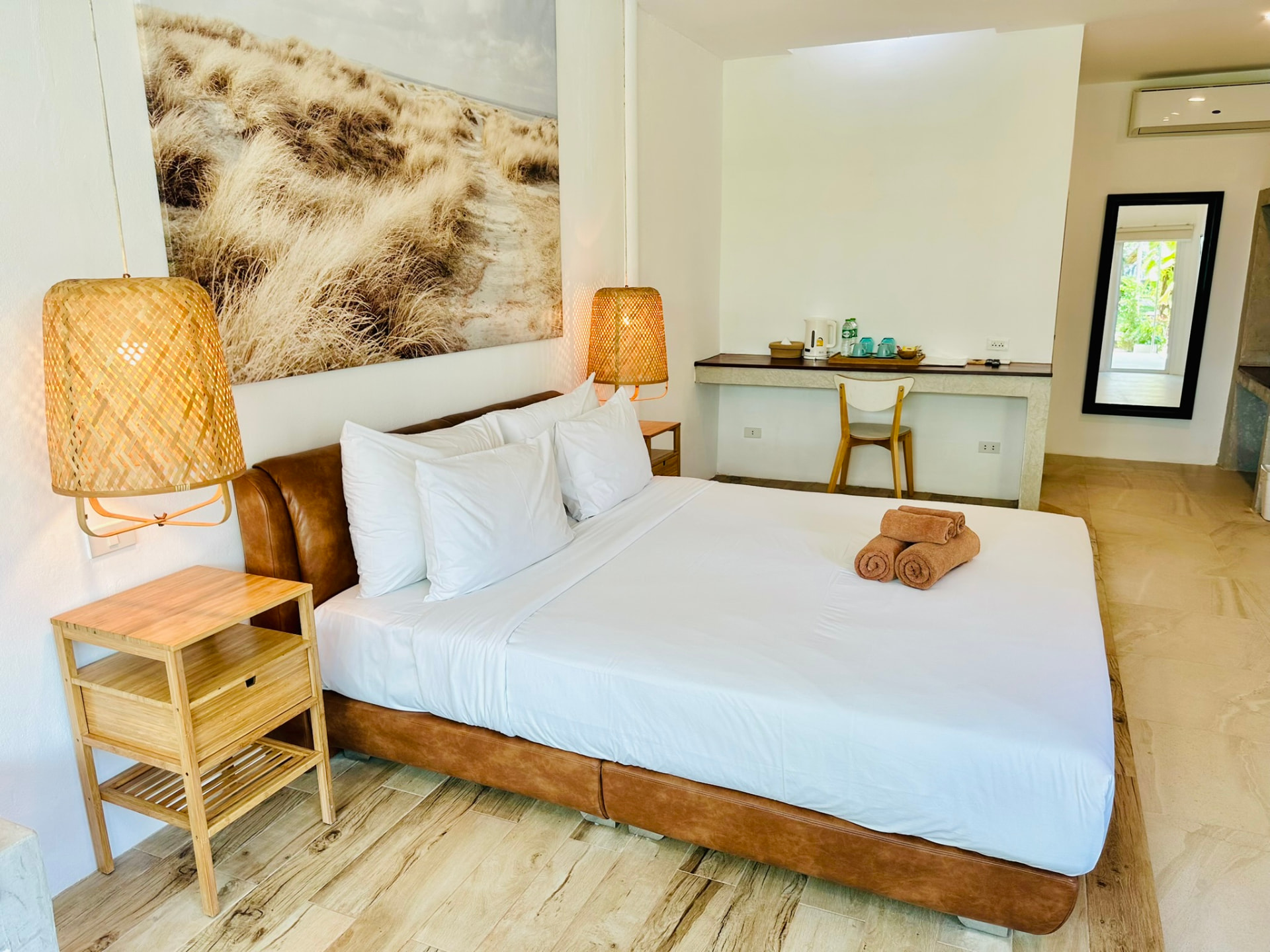 King bed with rattan pendant lights and a long writing desk beyond