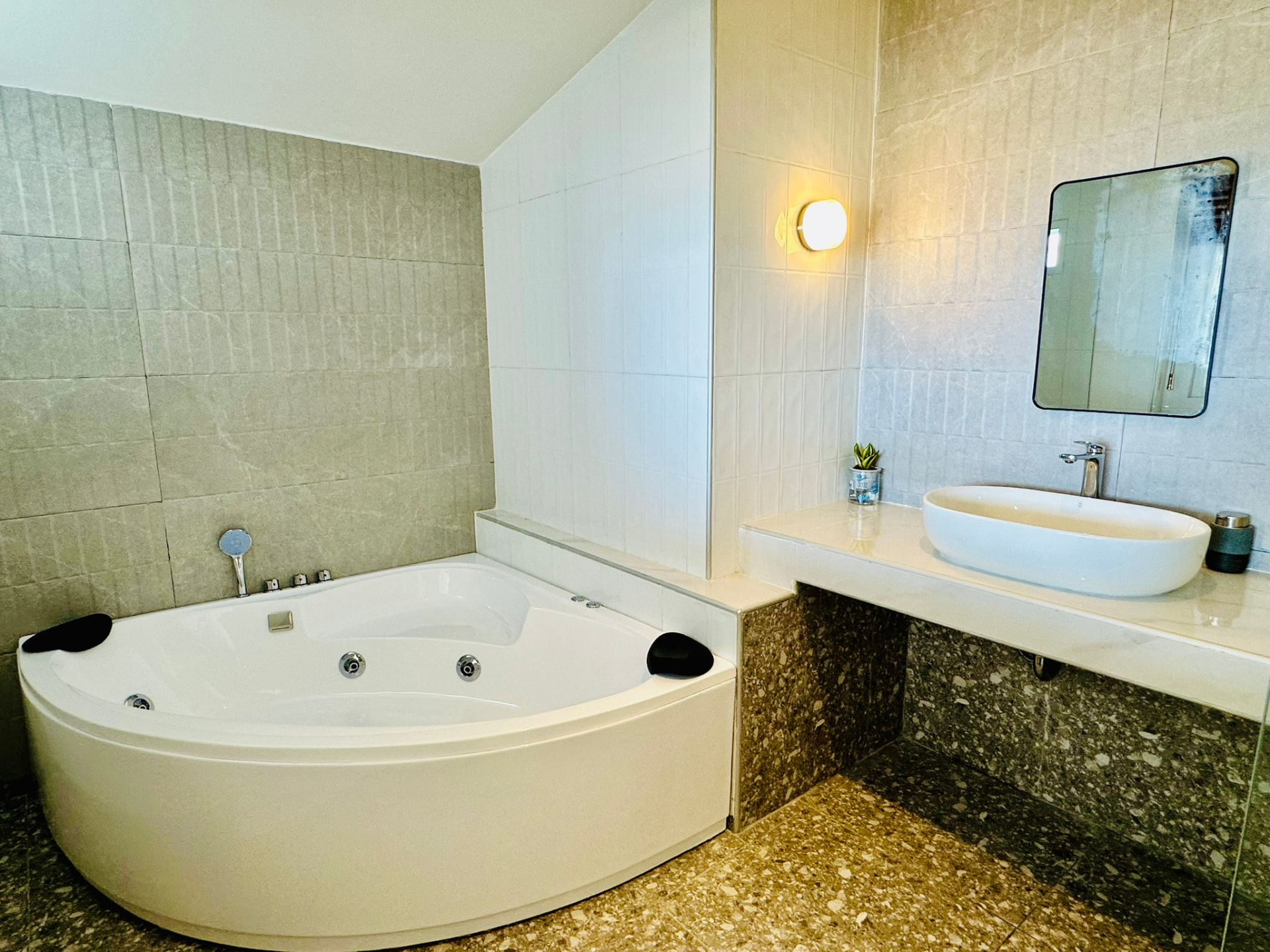 Corner jacuzzi bathtub beside a stone vanity with a vessel basin