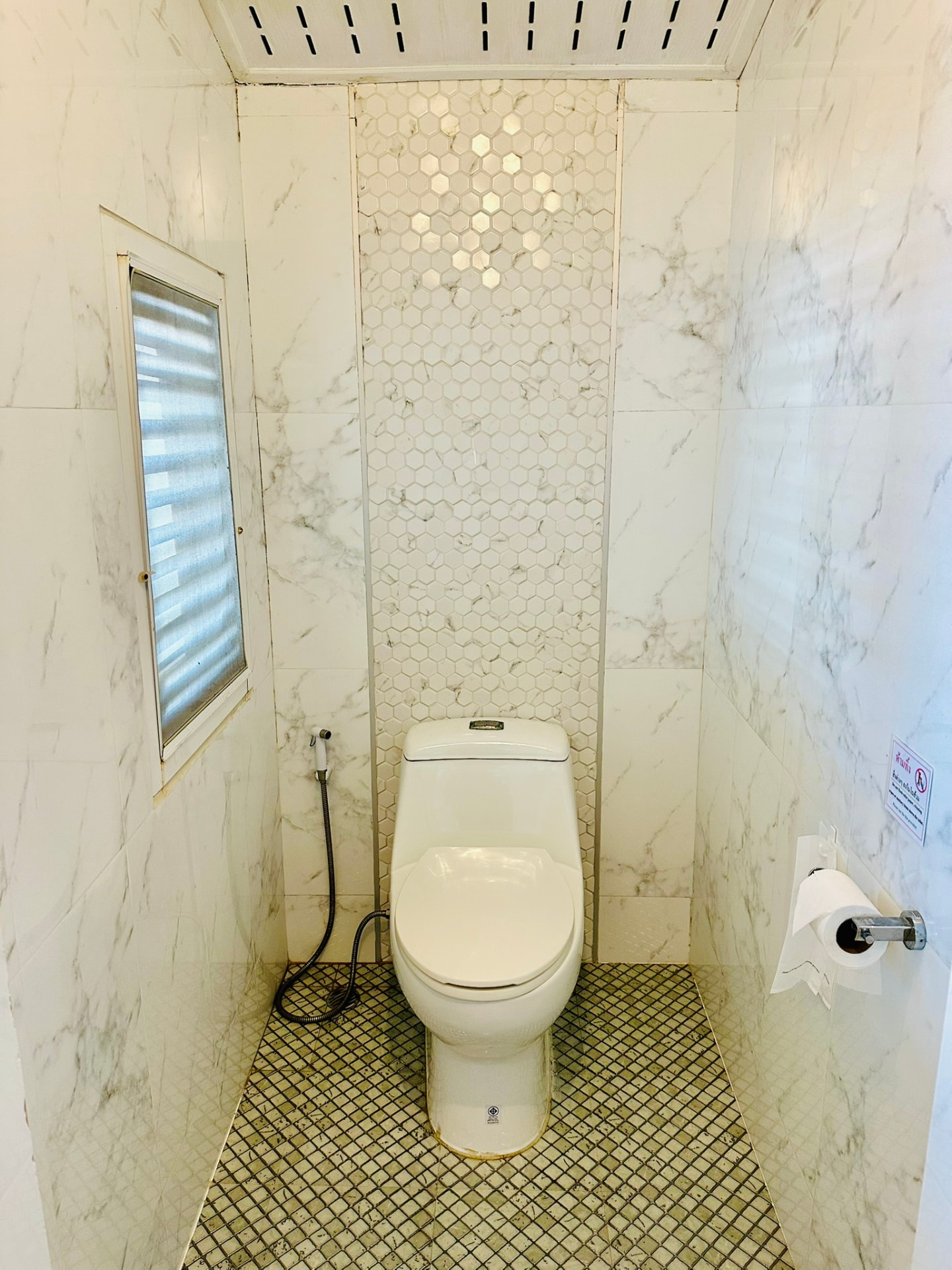 Marble-tiled toilet with hexagon tile detailing