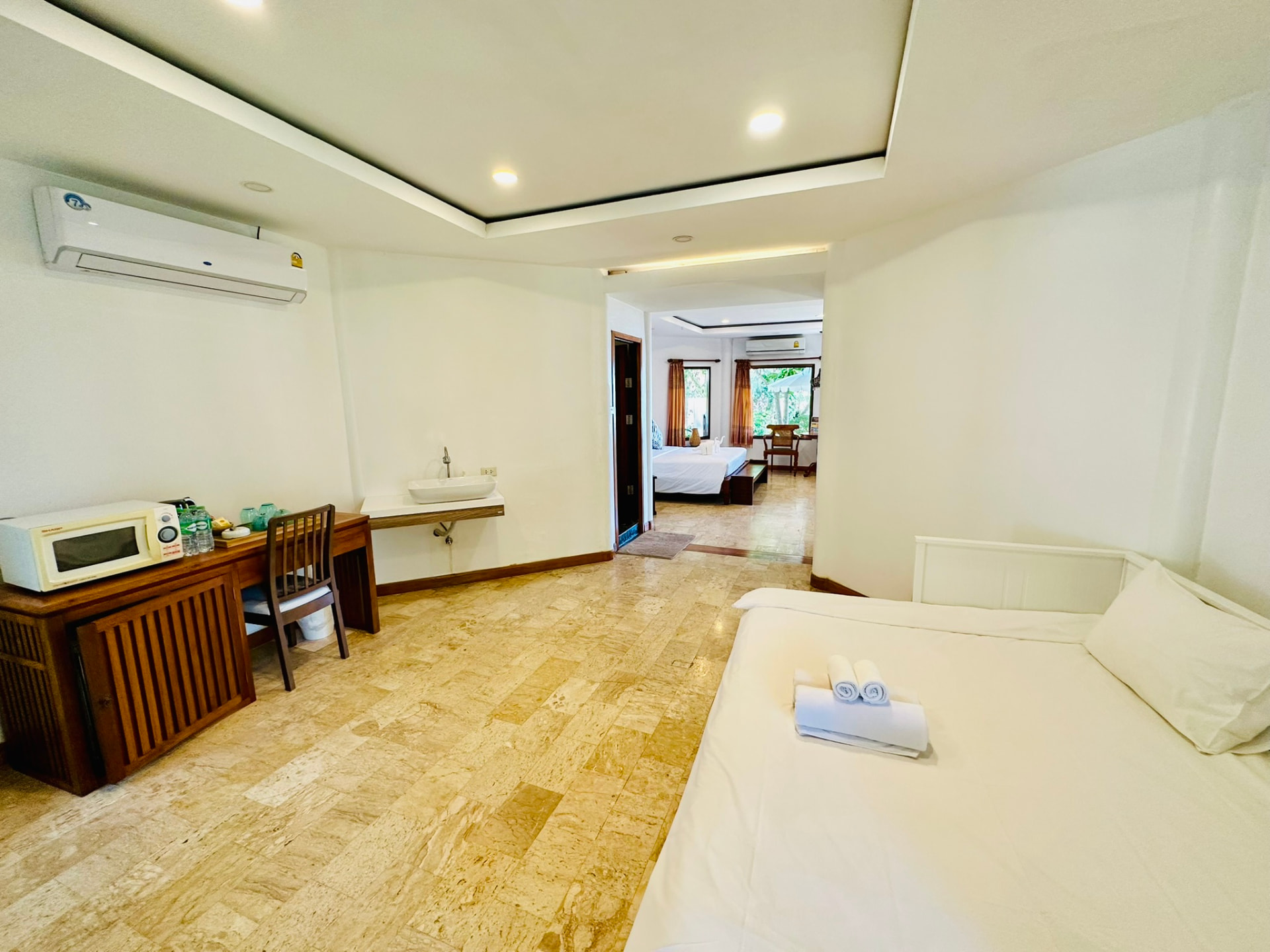 Second room with a day bed, desk and basin looking back towards the main bedroom