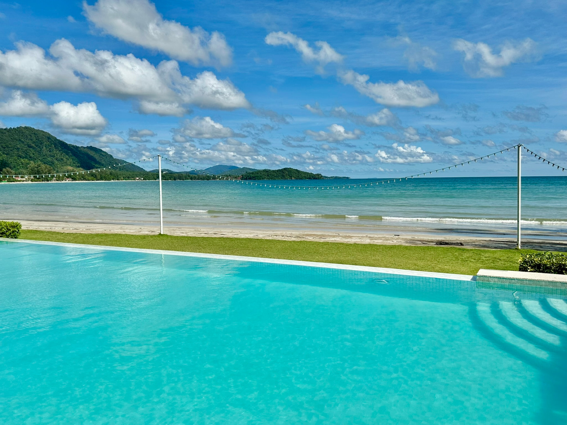 The pool, lawn and beach with the headland in the distance