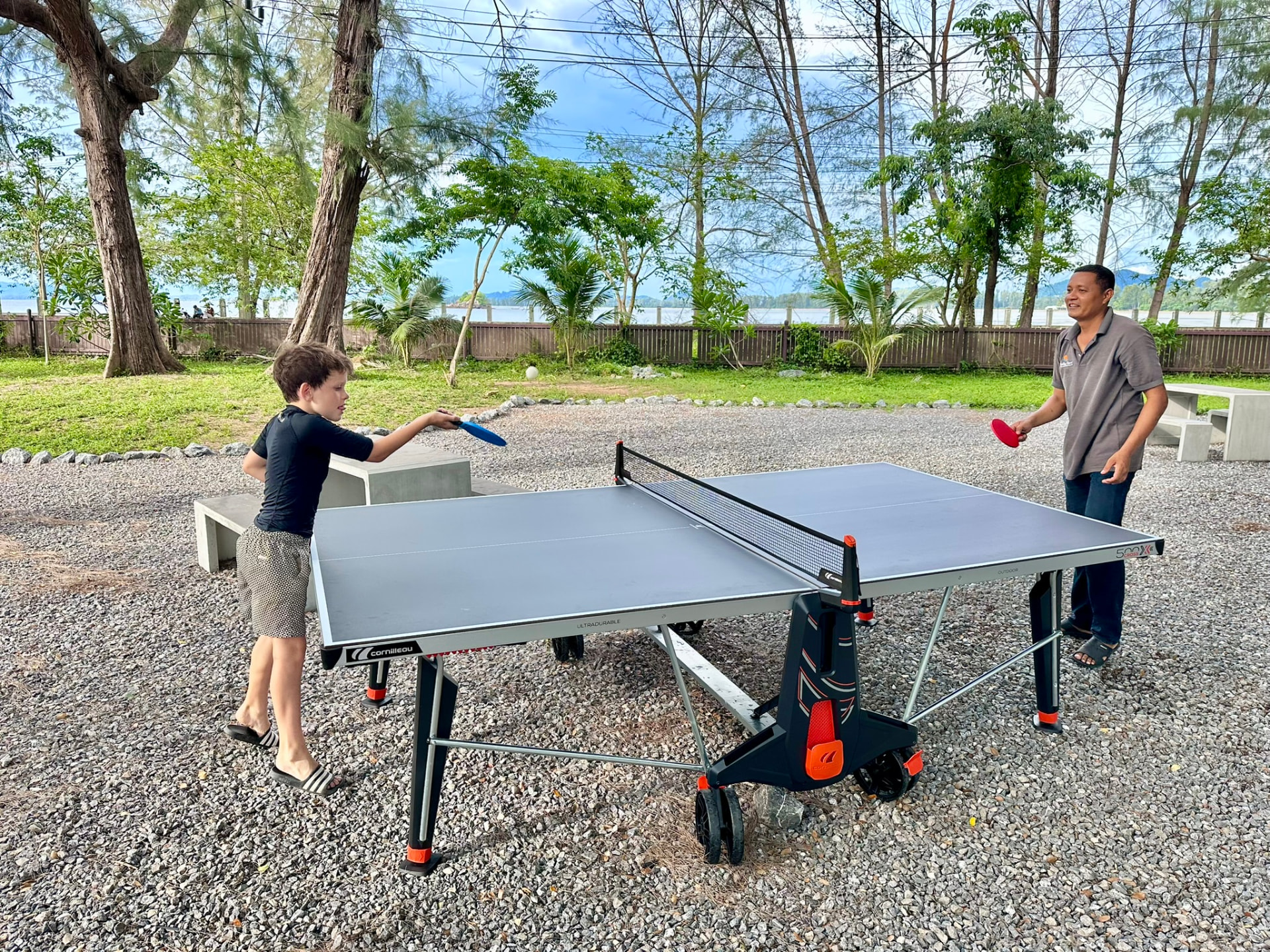 A young guest playing table tennis with a TwinBay team member