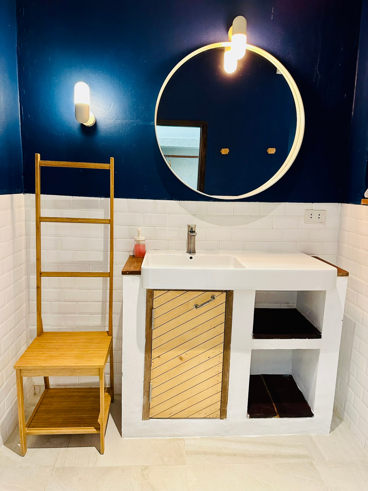 Bathroom with a deep basin, round mirror and deep blue and white tiled walls