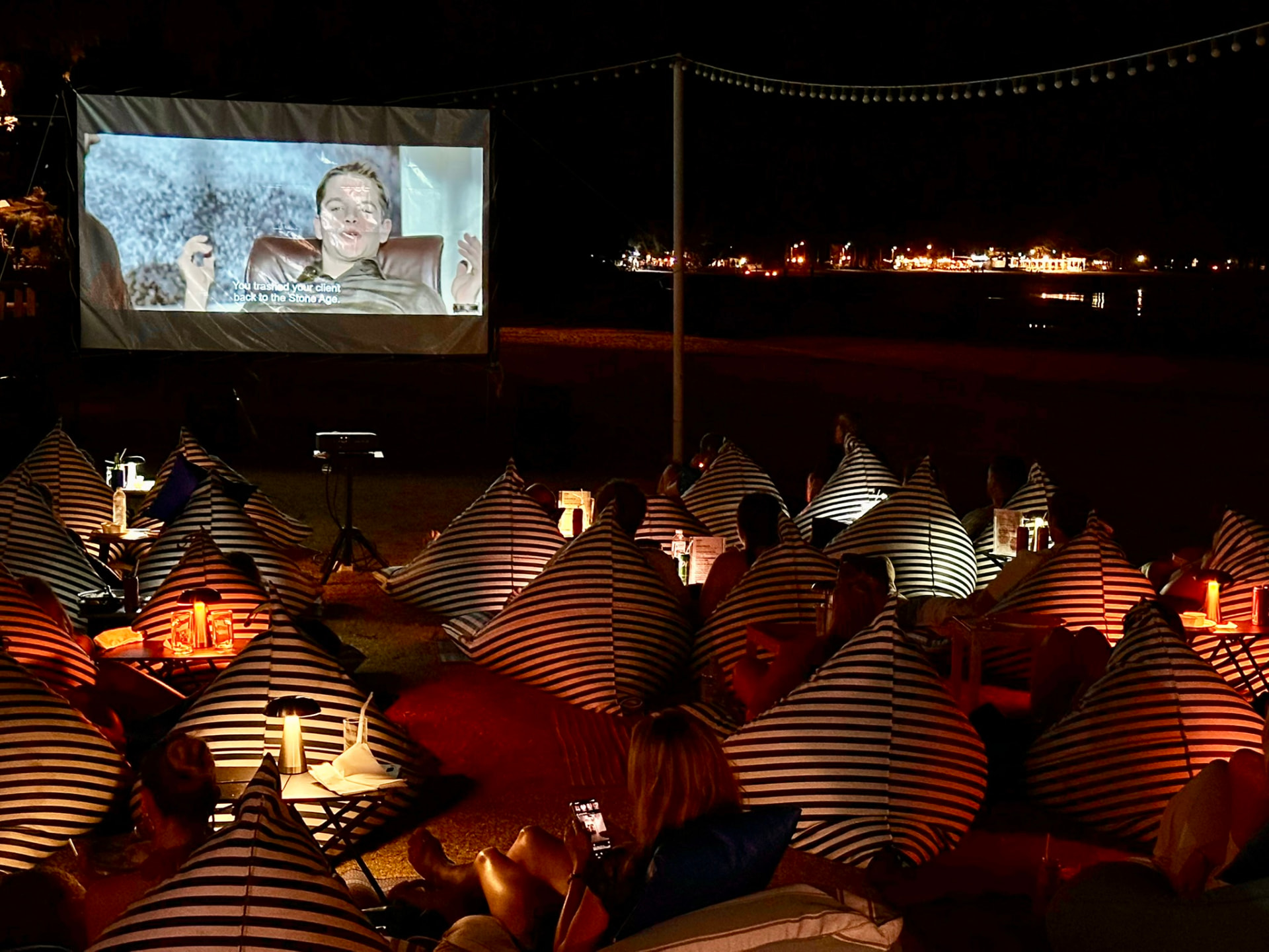 Table lanterns glowing between bean bags during a film on the beach