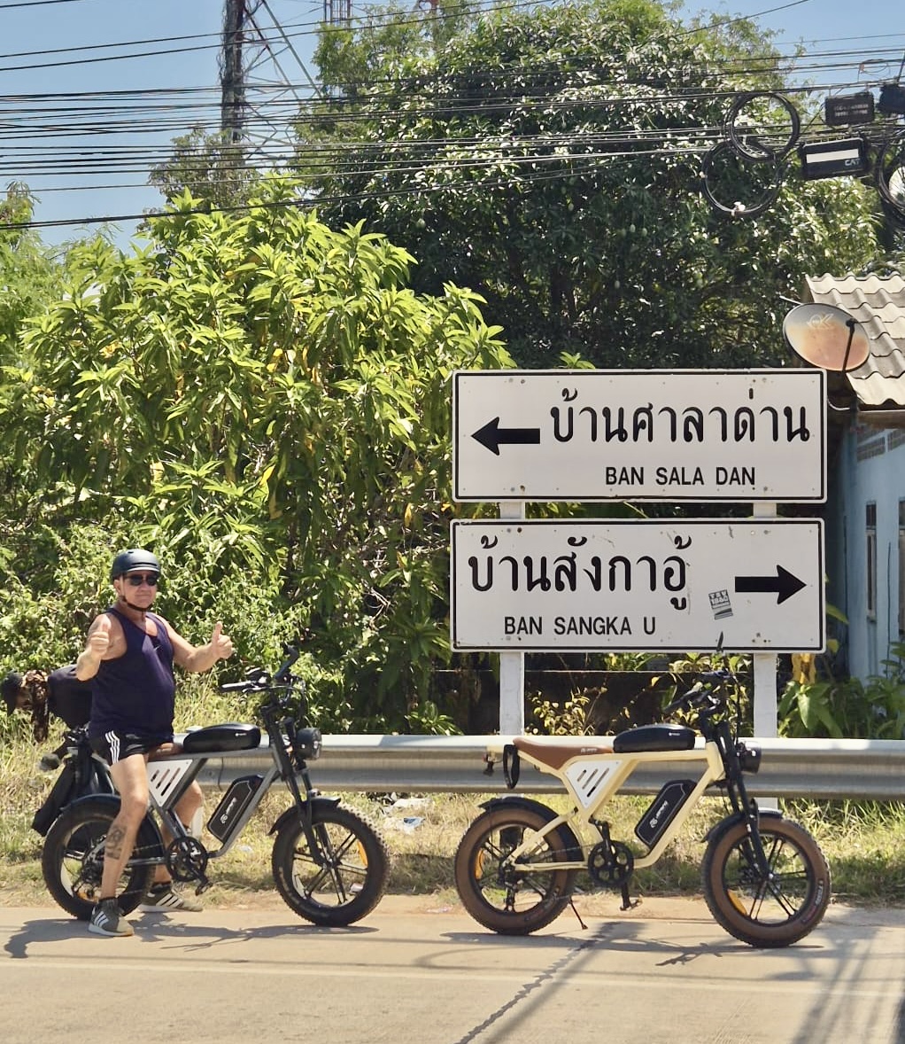 A guest with both thumbs up beside road signs to Ban Sala Dan and Ban Sangka U