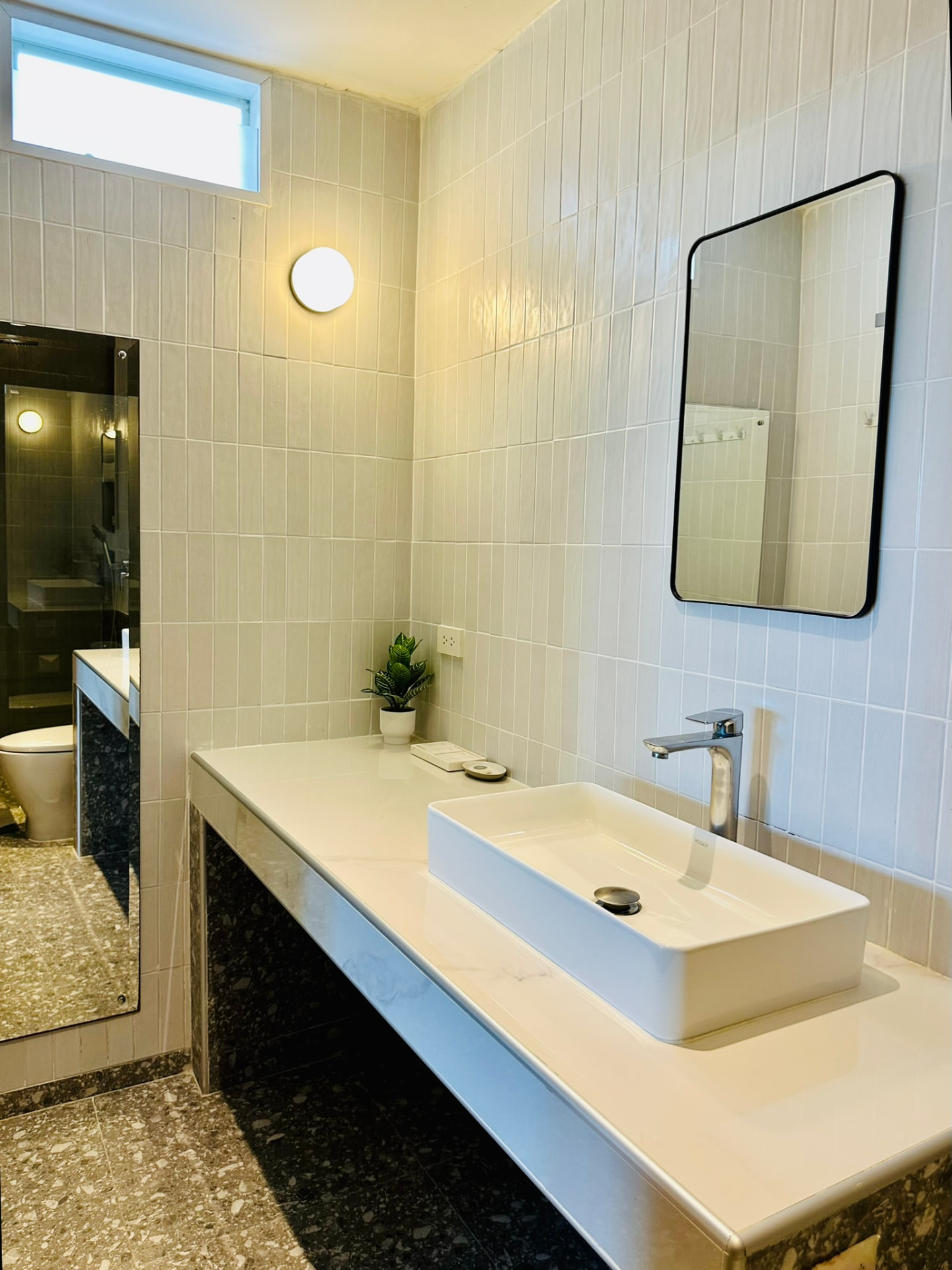 Bathroom with a wide basin, mirror and pale tiled walls