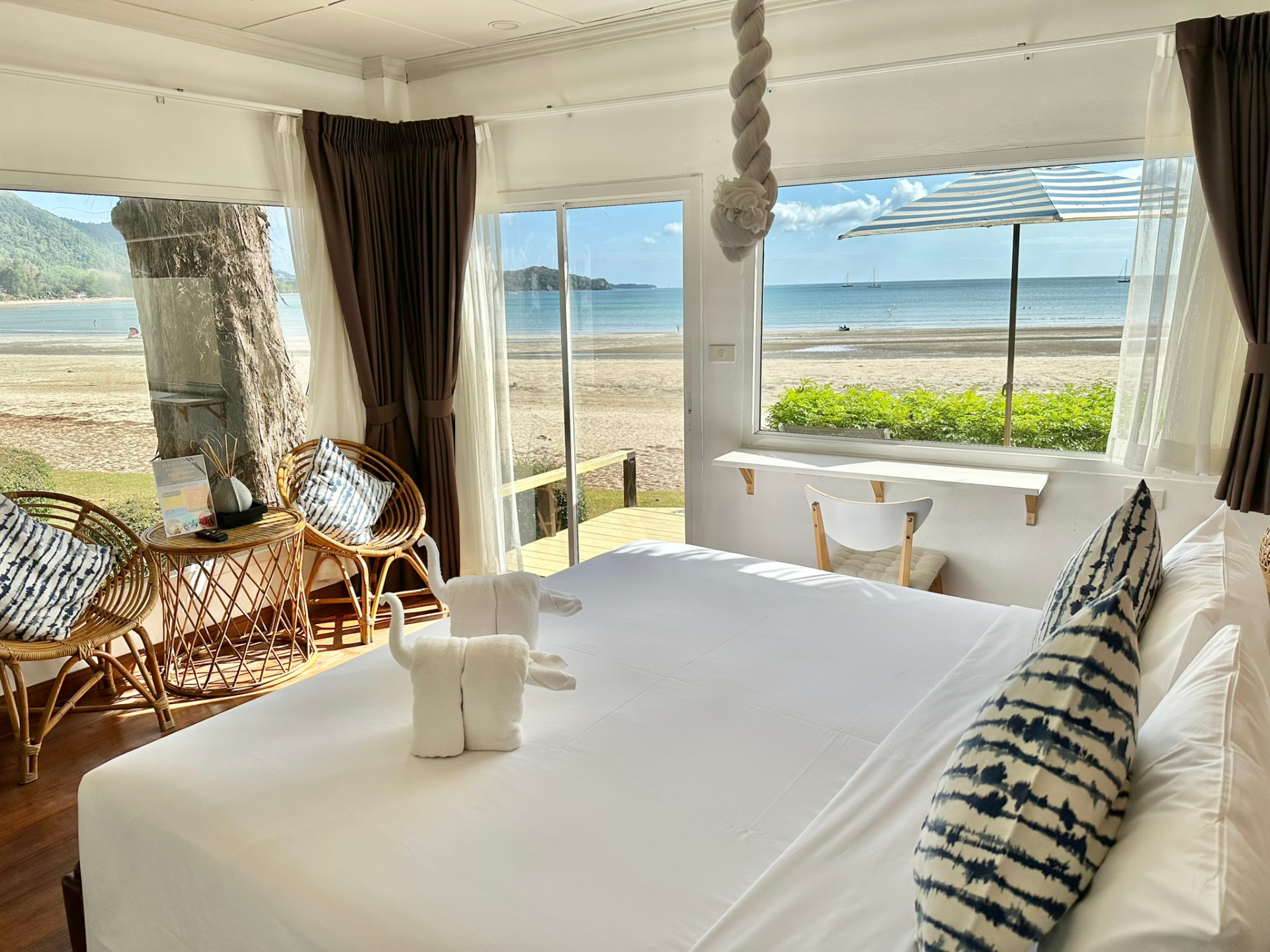 King bed in a bright corner bungalow with windows on two sides looking straight onto the sand and the bay