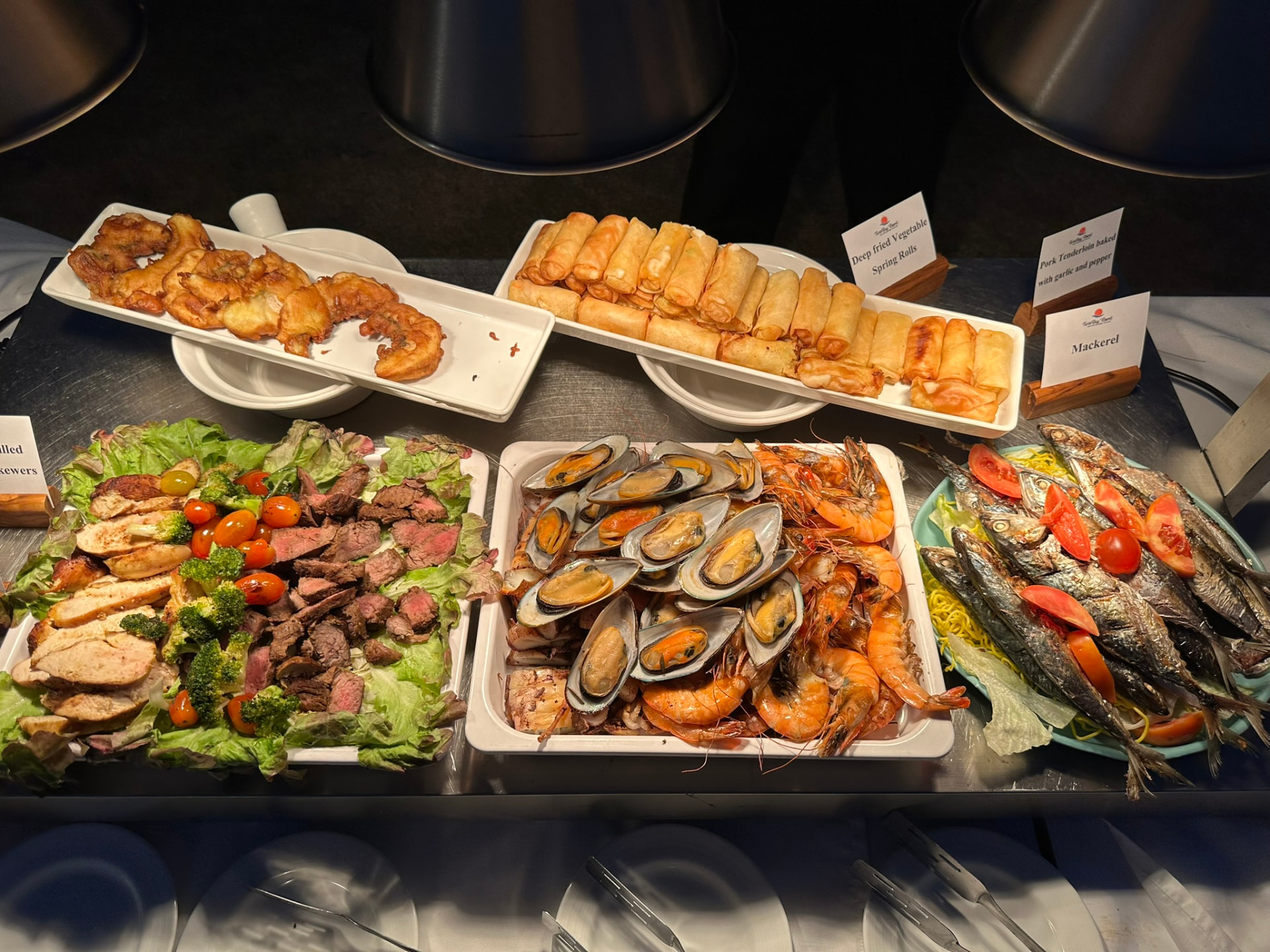 Platters of grilled seafood, mussels, prawns, spring rolls and salad on the buffet line
