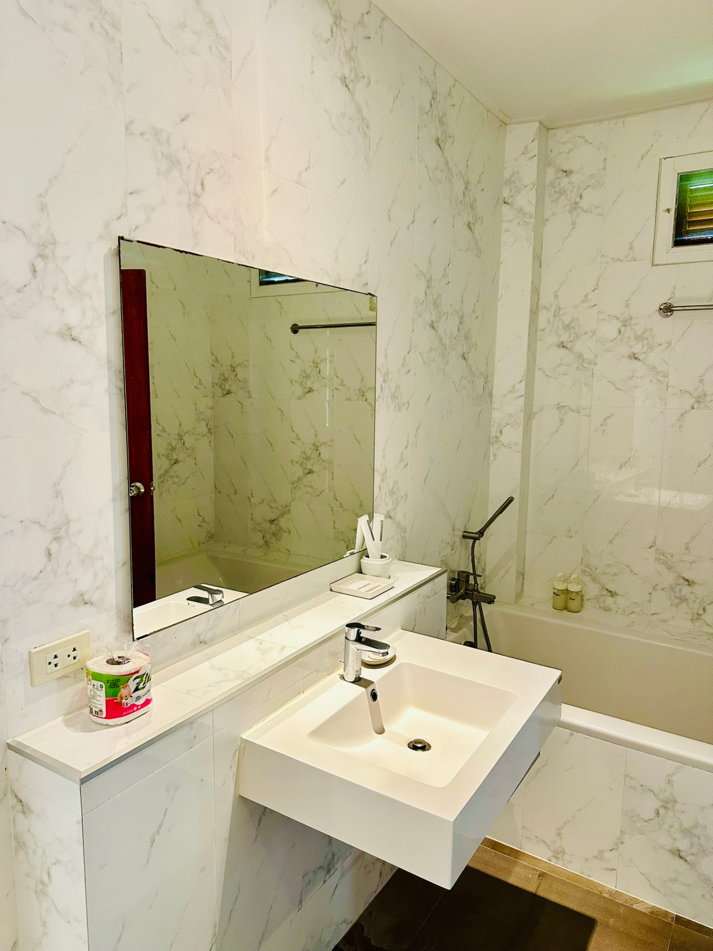 Marble bathroom with a bathtub, hand basin and wide mirror