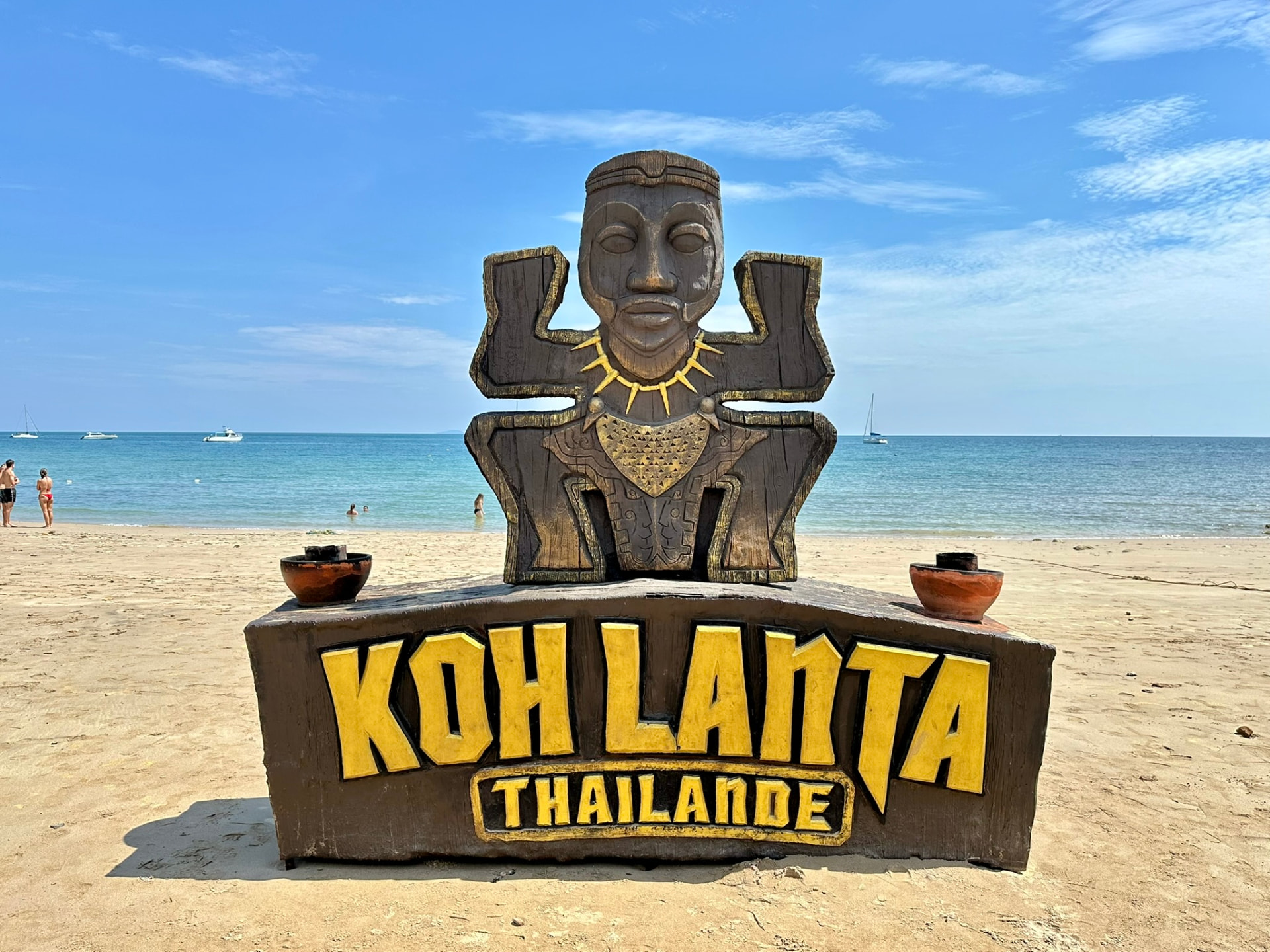The wooden Koh Lanta Thailand sign on the sand with the sea behind