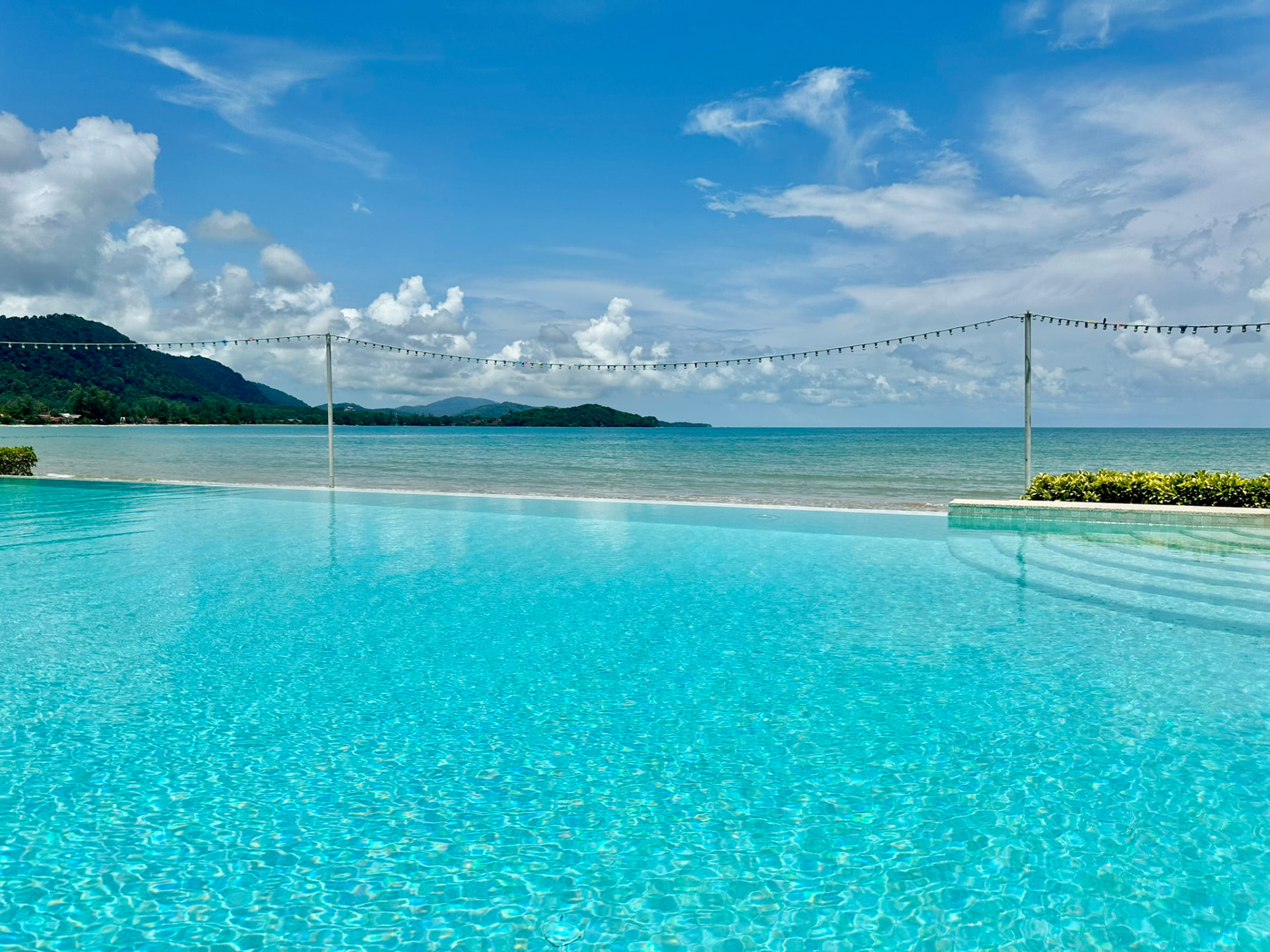 Turquoise pool water with the bay and green hills beyond