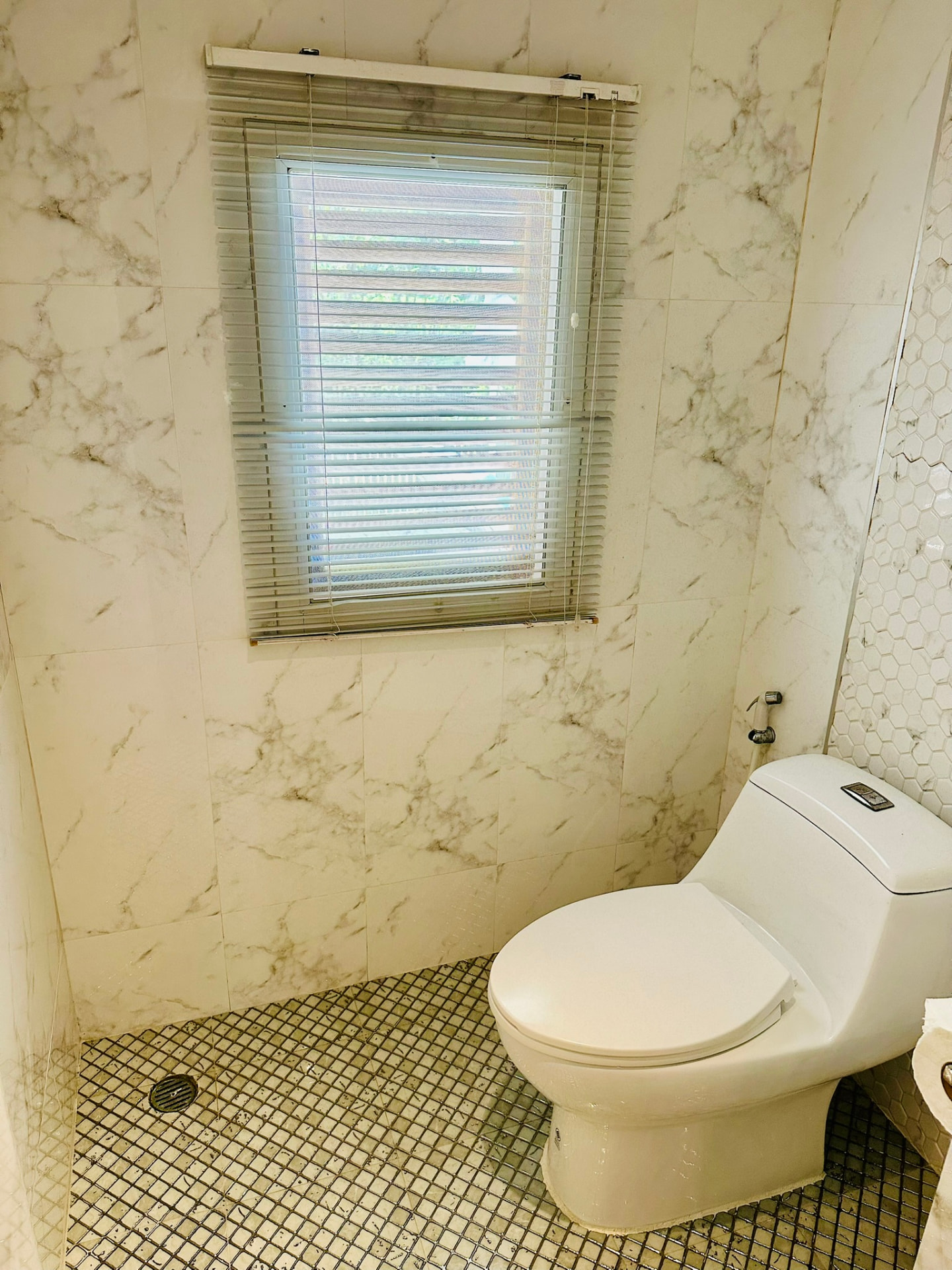 Marble-tiled toilet area with a shuttered window