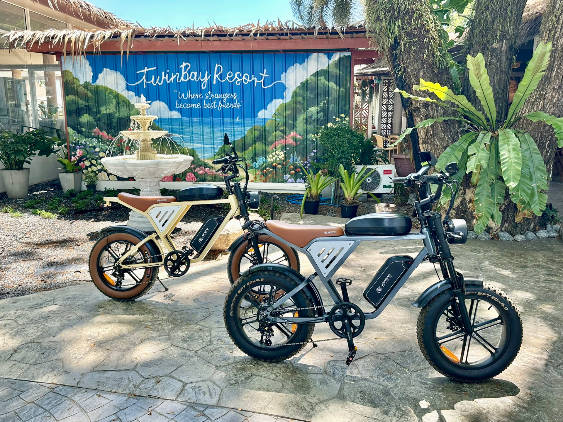 E-bikes parked in front of the TwinBay Resort mural and fountain