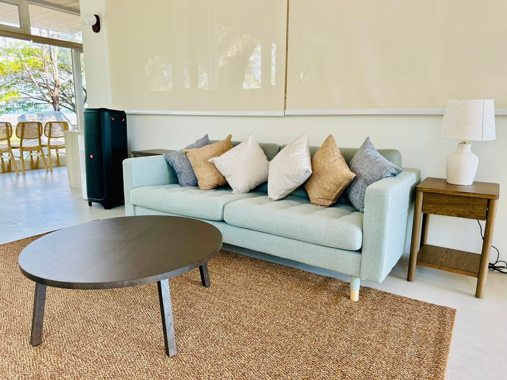 A pale green sofa with linen cushions and a round coffee table on a jute rug