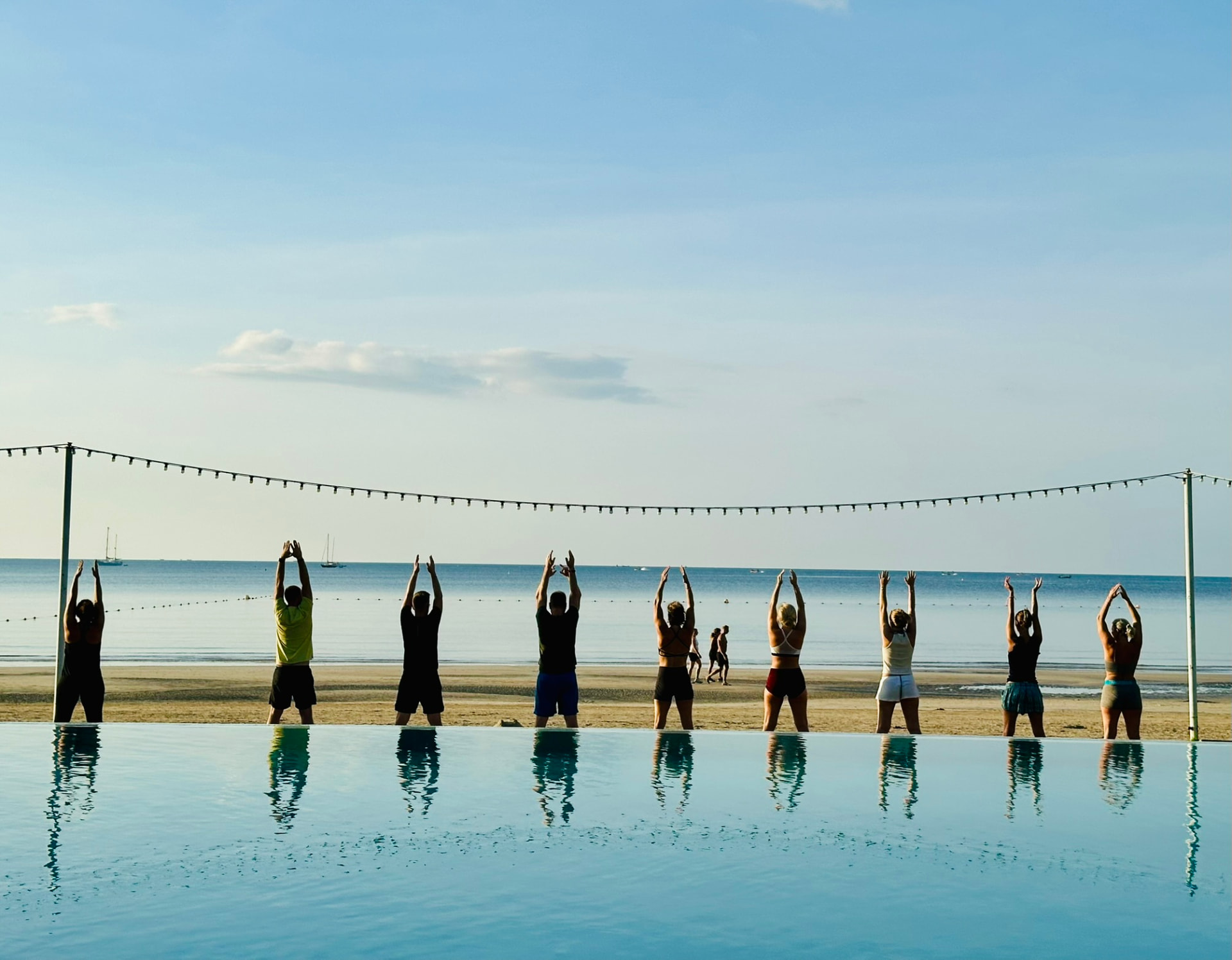 Guests reaching skyward at the infinity pool edge during morning yoga