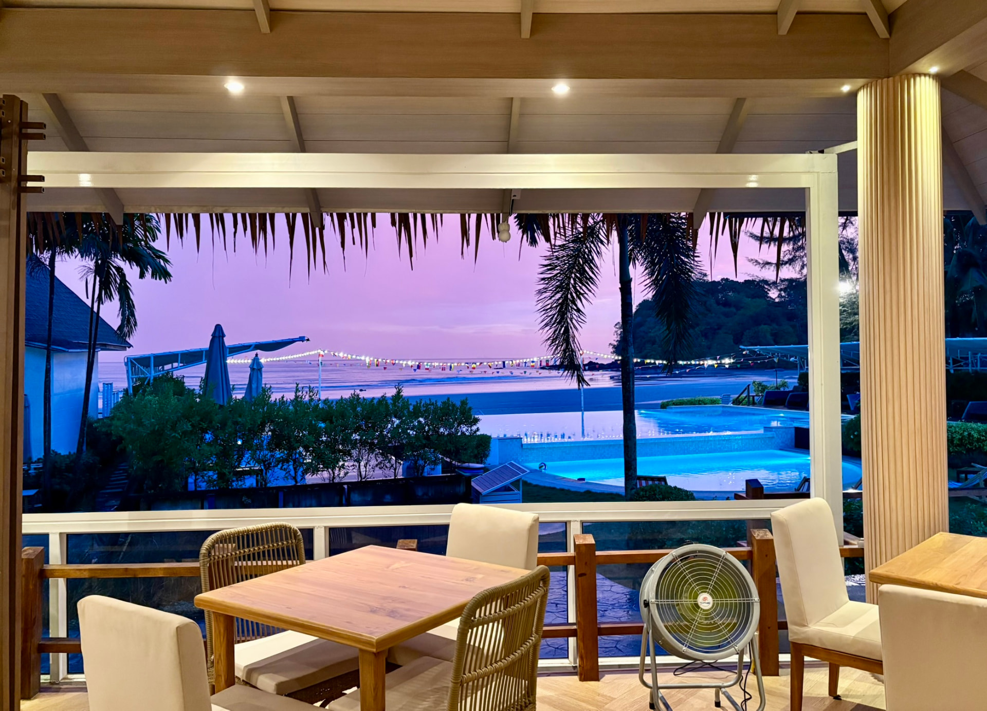 A table looking out over the pool and beach under a violet sunset sky