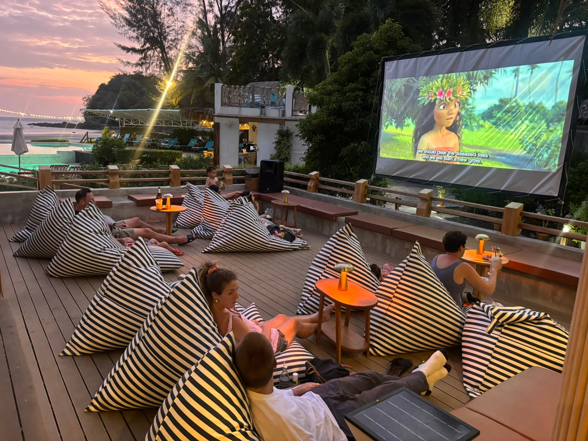 Families on striped bean bags watching a film at Breezy Bites as the sky turns pink