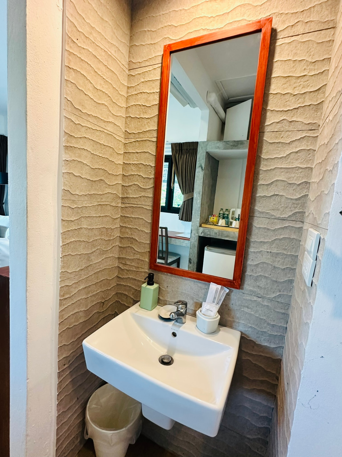 Hand basin with a timber-framed mirror against a textured sandstone wall