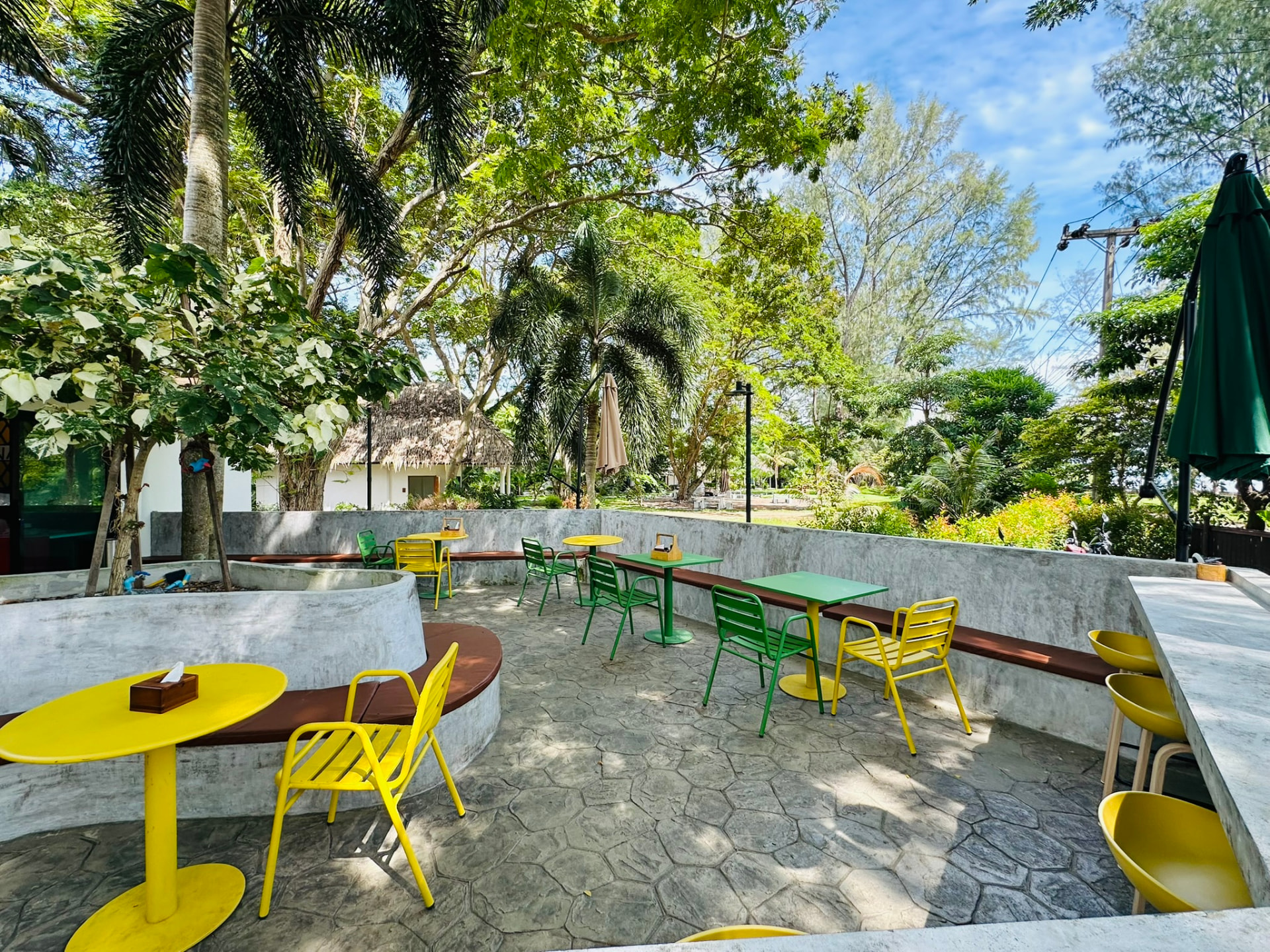 Garden seating at PineNapple Cafe with curved concrete benches and palms