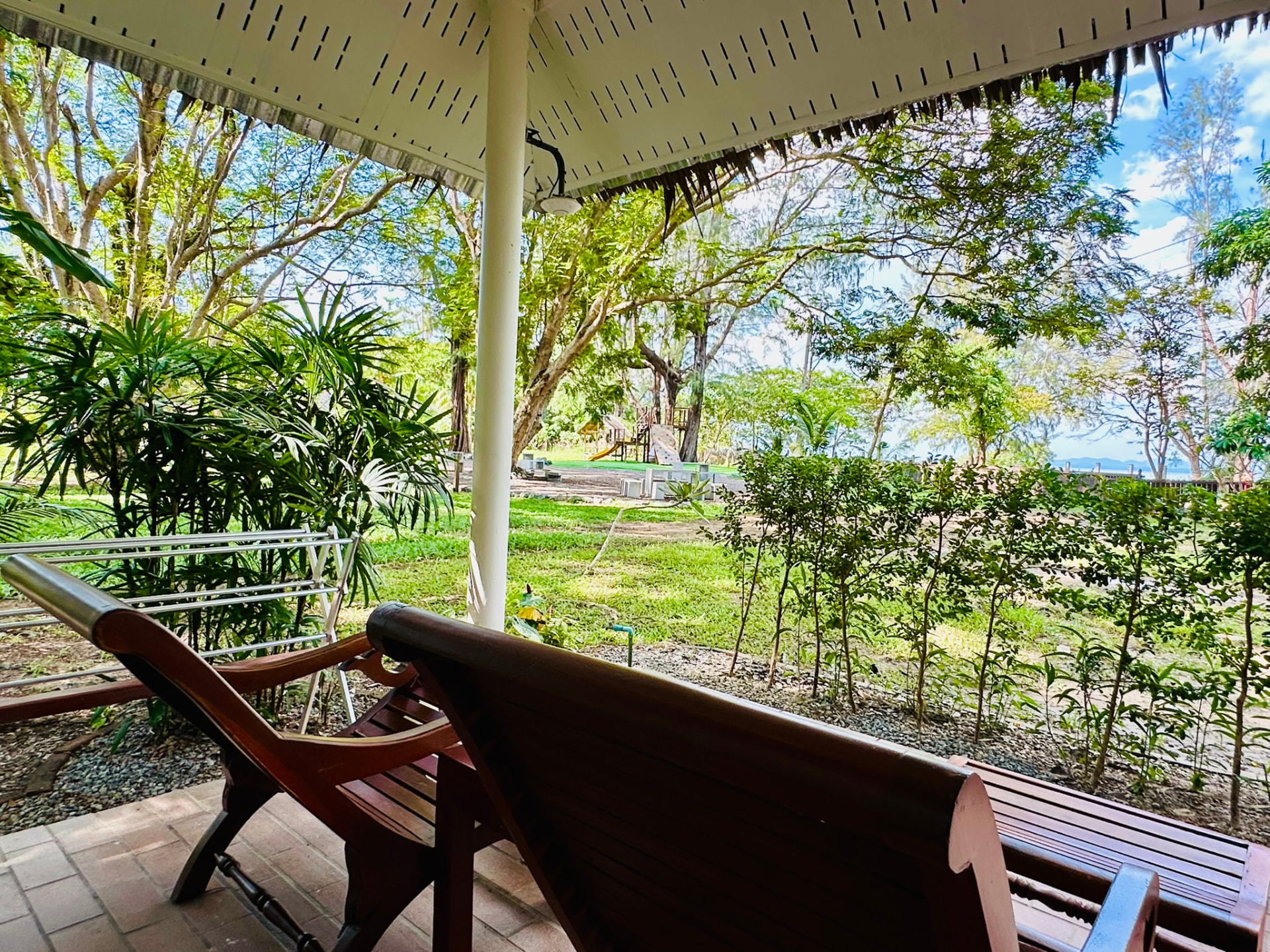 Wooden loungers on the bungalow terrace looking out over the garden towards the sea