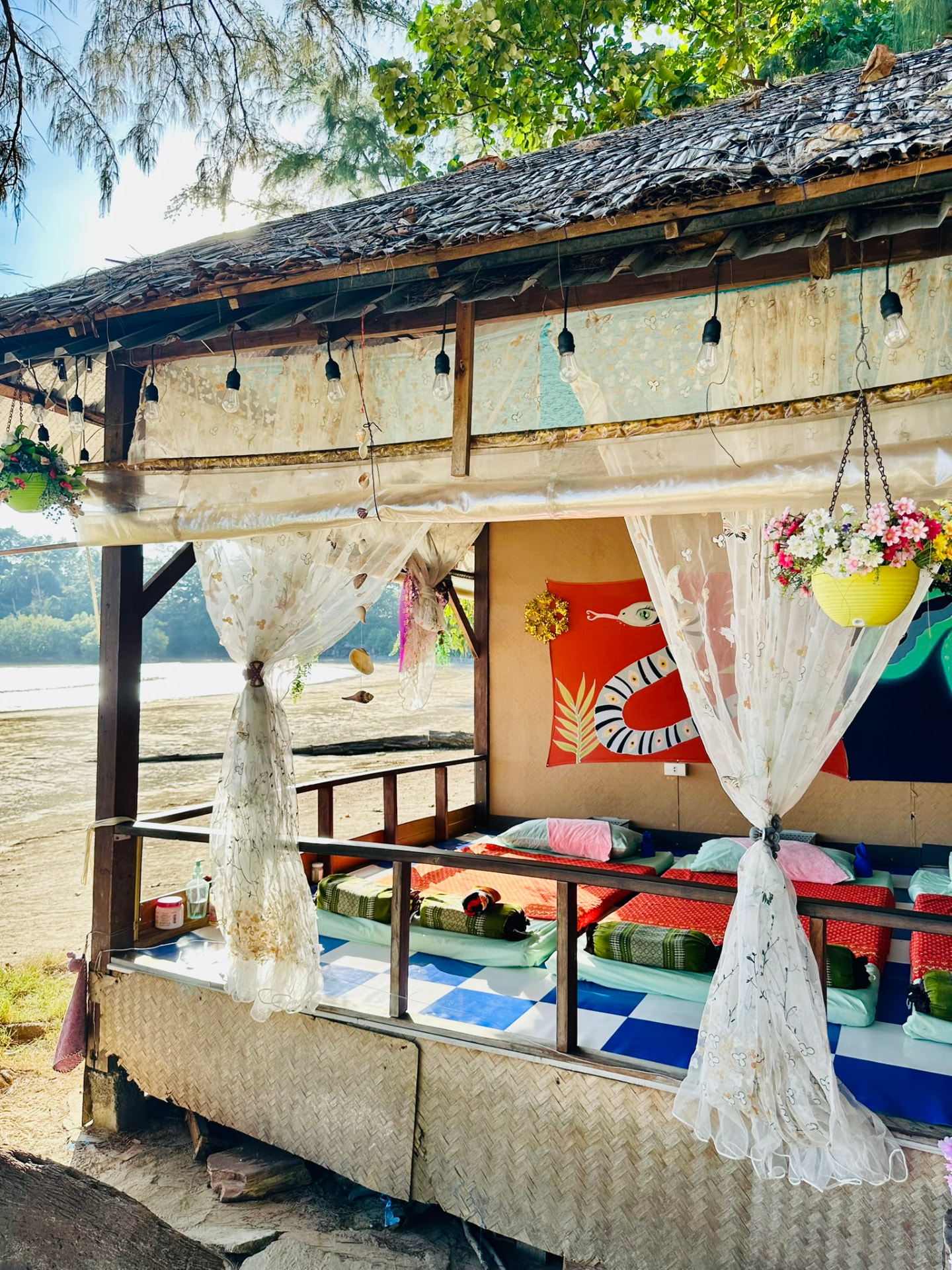The thatched massage sala with lace curtains and hanging flowers on the beach