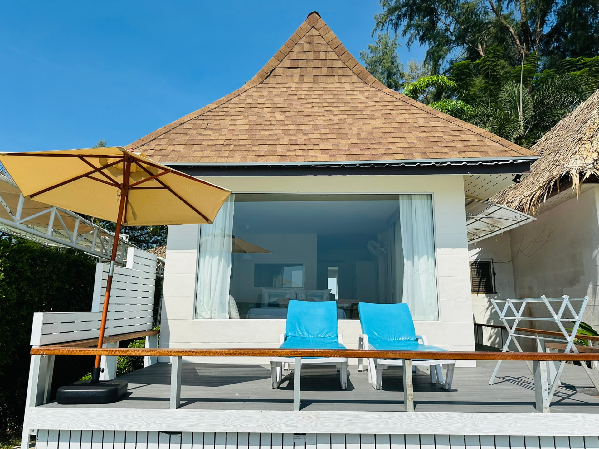 Bungalow exterior with a private deck, sunbeds and a yellow parasol