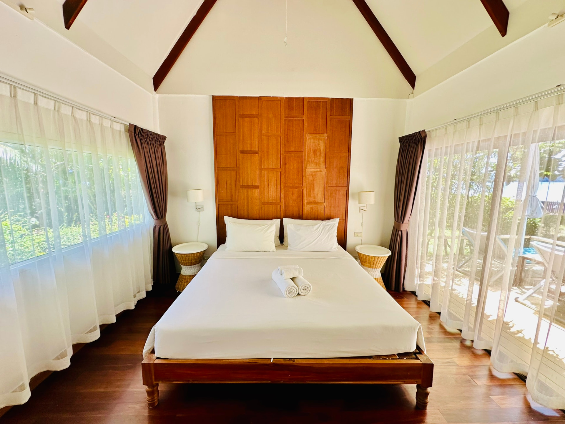 King bed centred between sheer-curtained glass doors on both sides