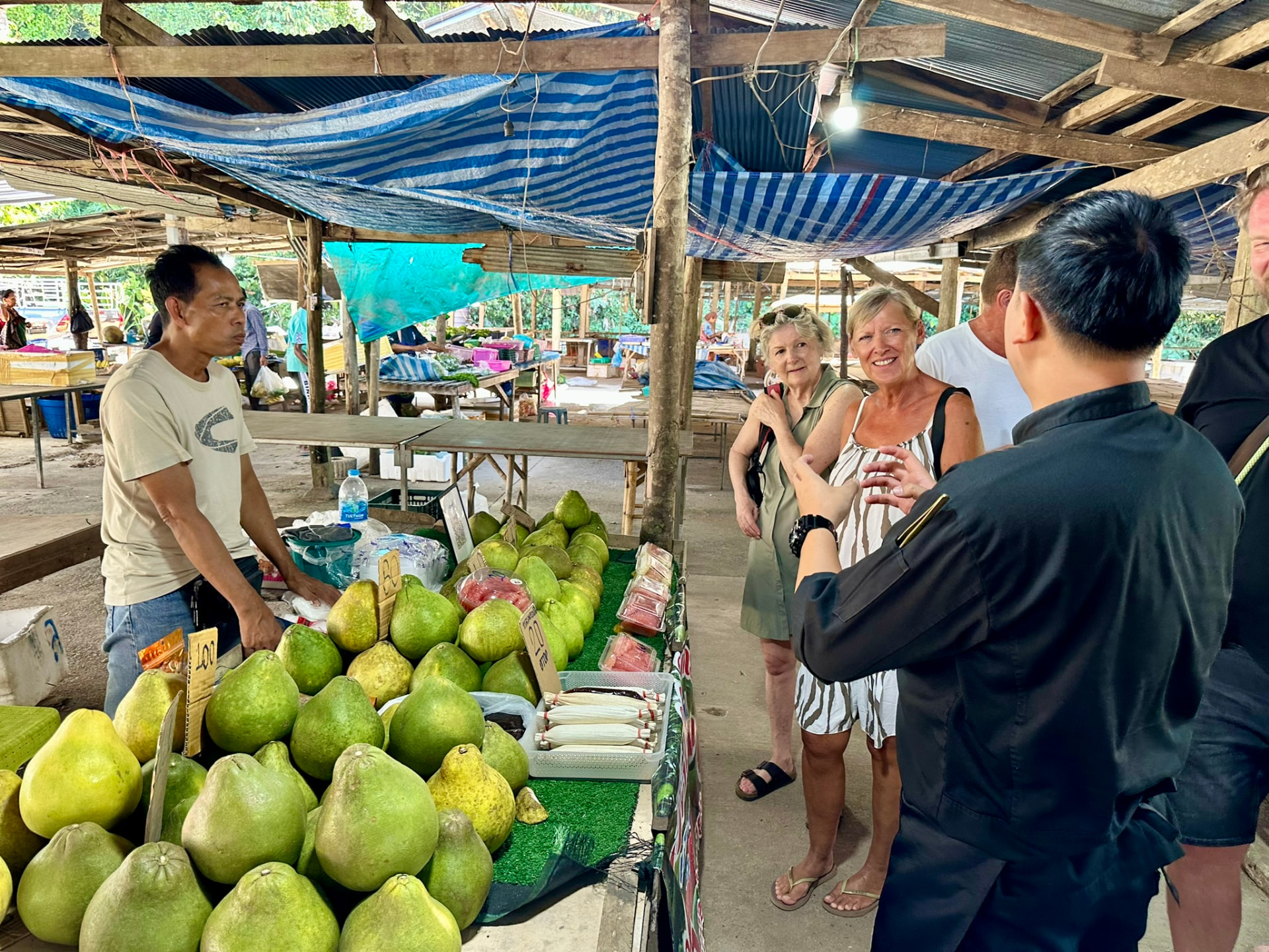 Guests and the chef choosing pomelo and vegetables at the local market