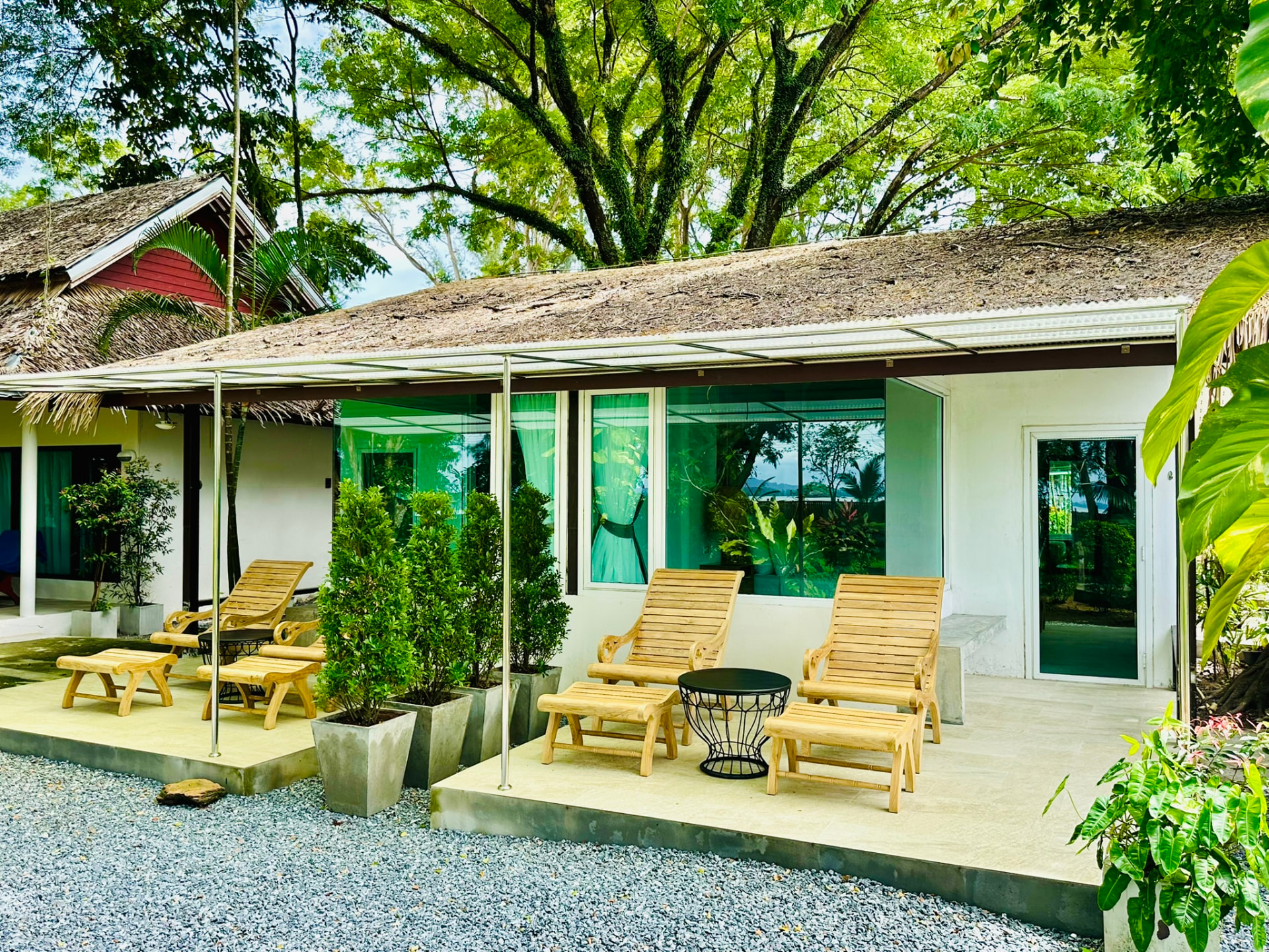 Teak loungers on a bungalow terrace surrounded by greenery