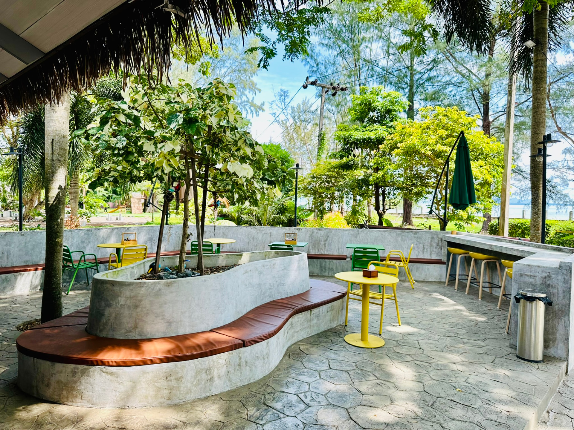 Curved bench and bar stools under the thatched roof at PineNapple Cafe