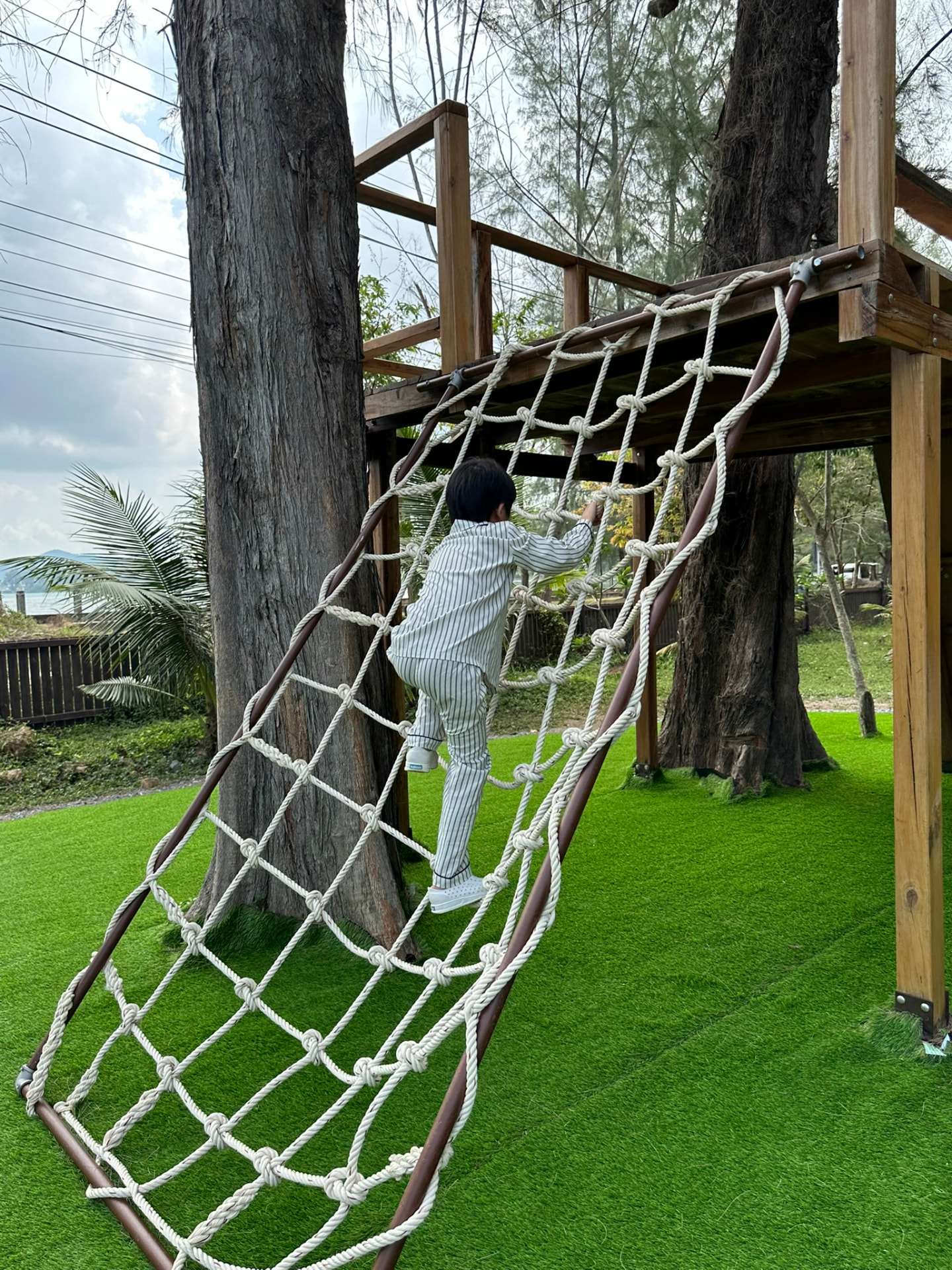 A child climbing the rope net up to the treehouse platform