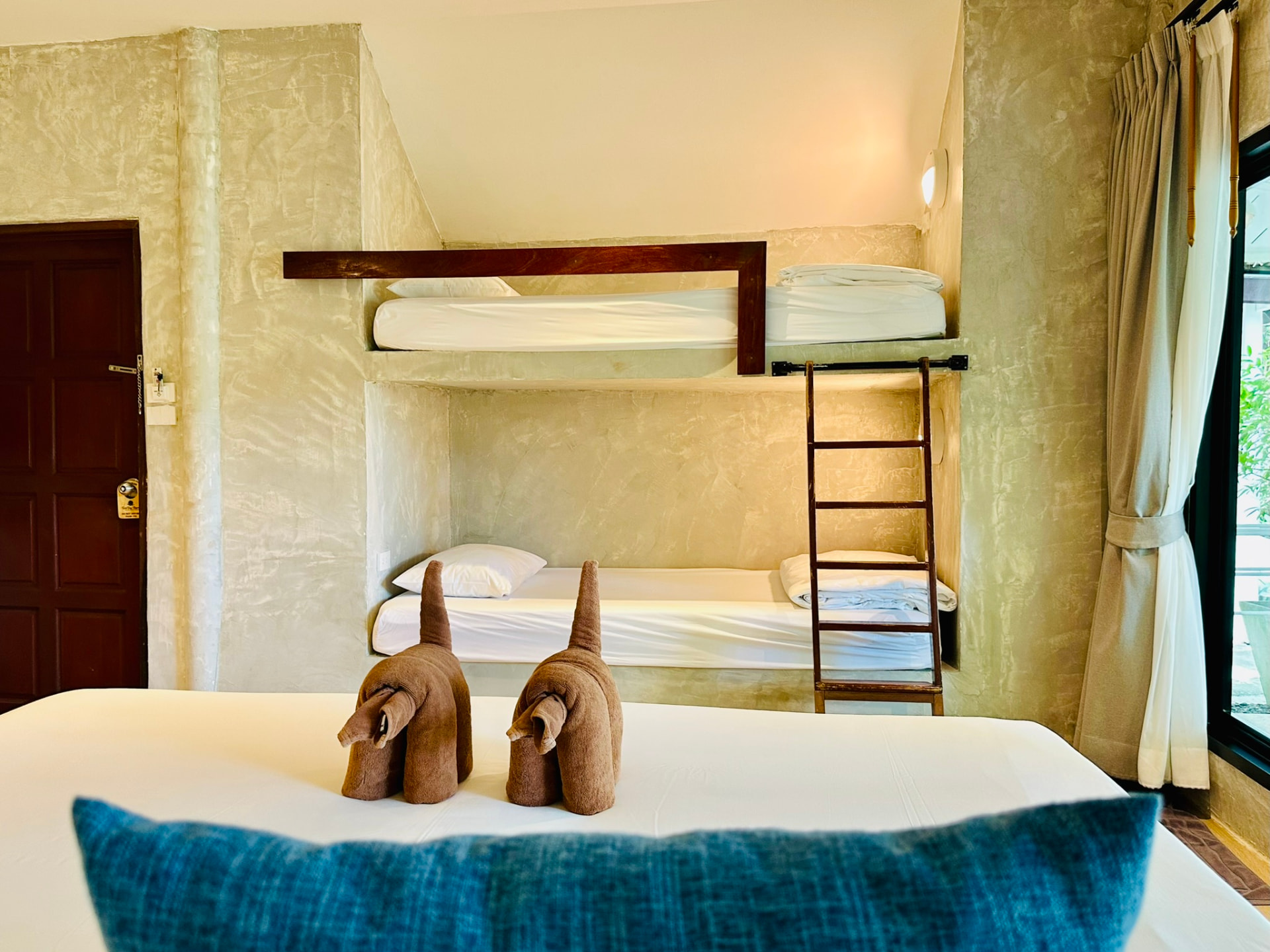 Two bunk beds in a polished plaster alcove with towel elephants on the king bed