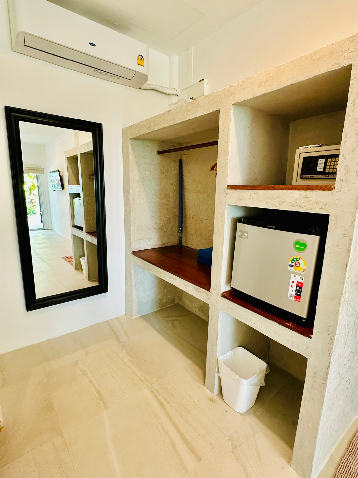 Open wardrobe niches with a safe, mini fridge and a full-length mirror