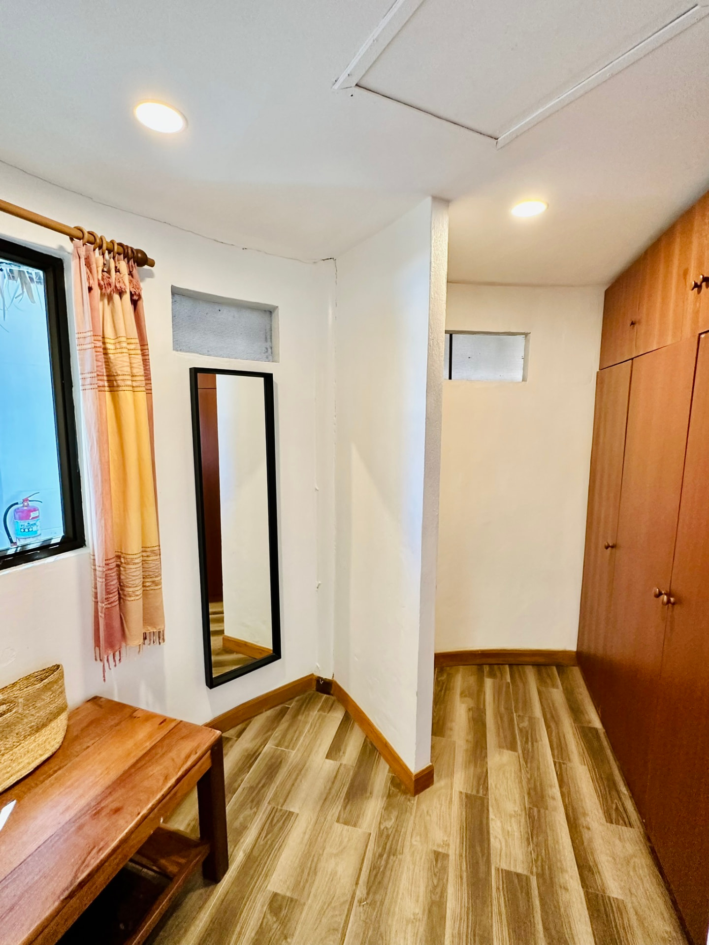 Dressing area with a full-length mirror, timber wardrobes and a bench