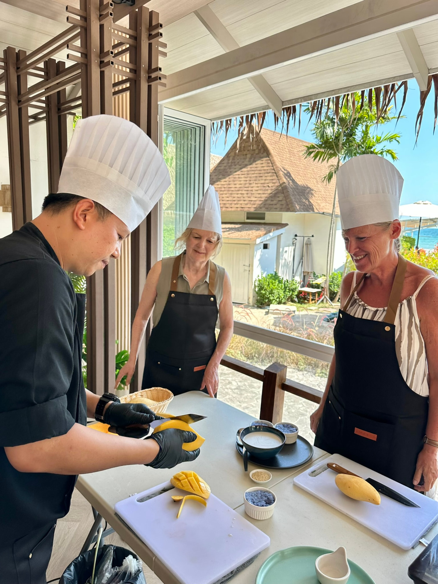 The chef carving mango while two guests watch