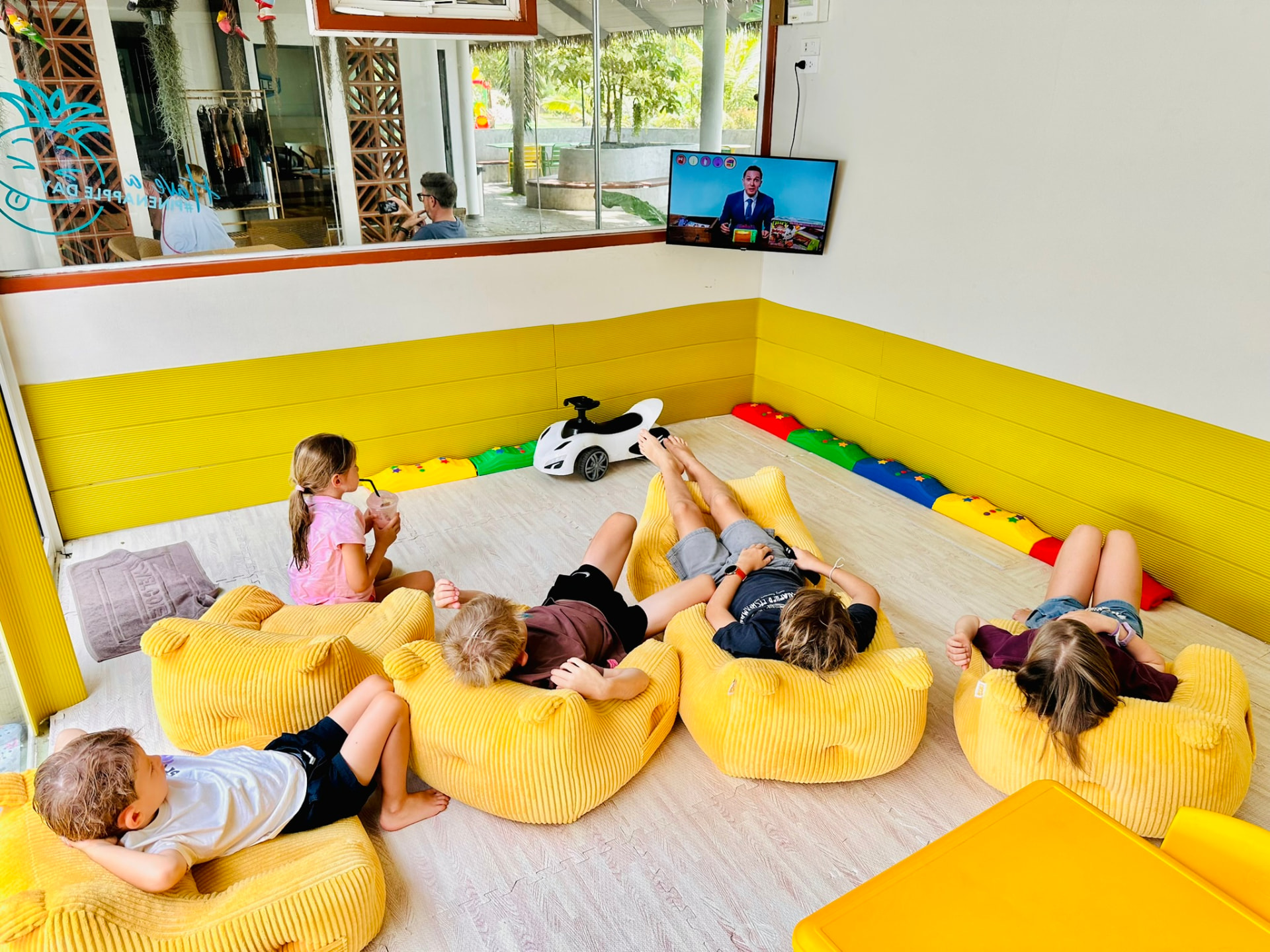 Children lying on yellow bean bags watching a film in the Kids Room