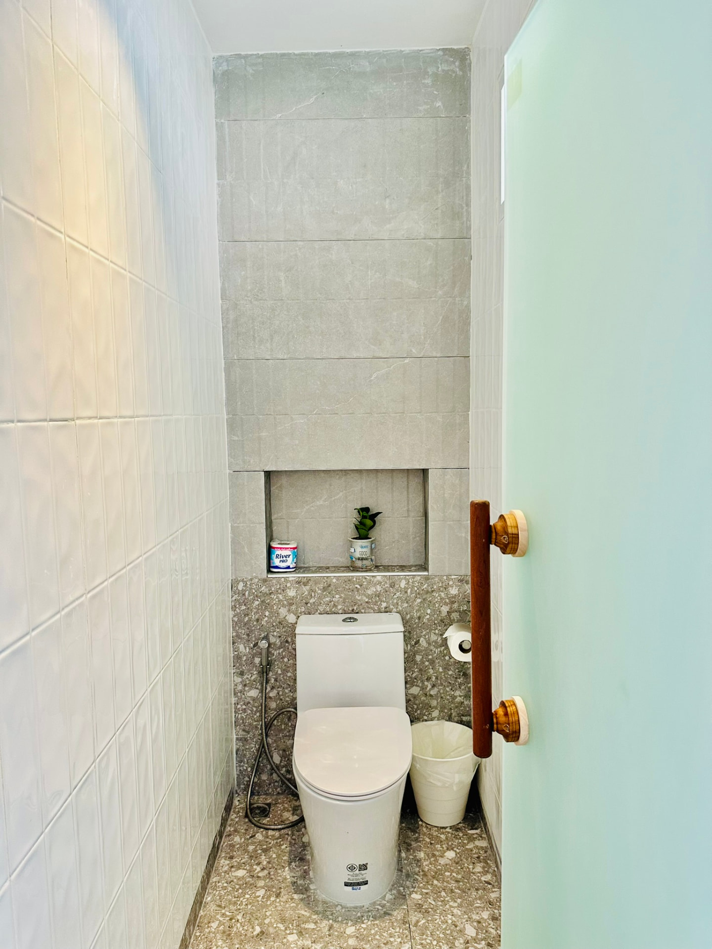 Separate toilet with stone tiling and a recessed shelf