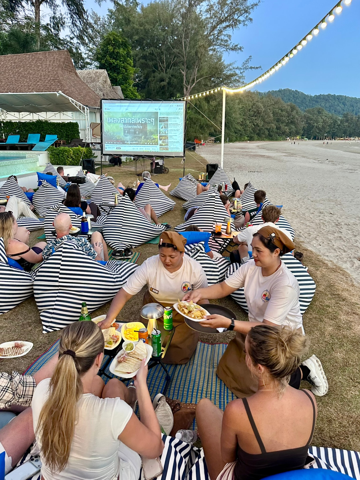 Two TwinBay team members serving food to guests on bean bags during the film