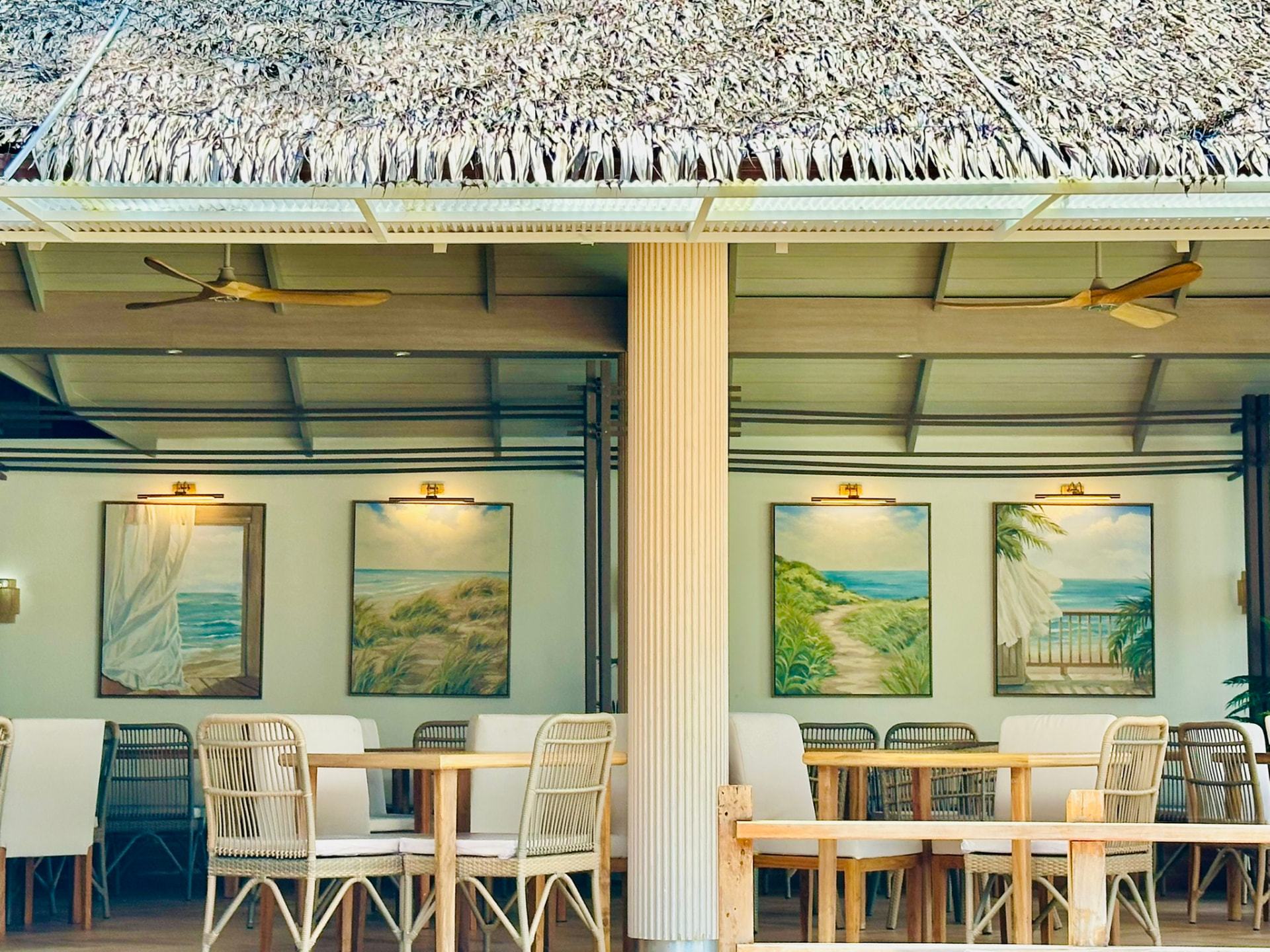 Thatched roof and seaside paintings above the tables at Breezy Bites