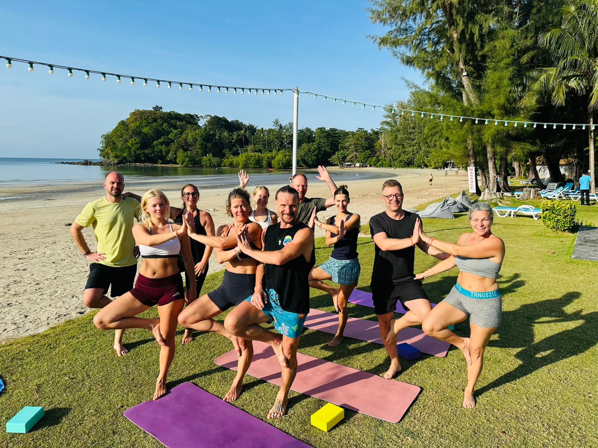 Smiling guests in tree pose together after a morning yoga class